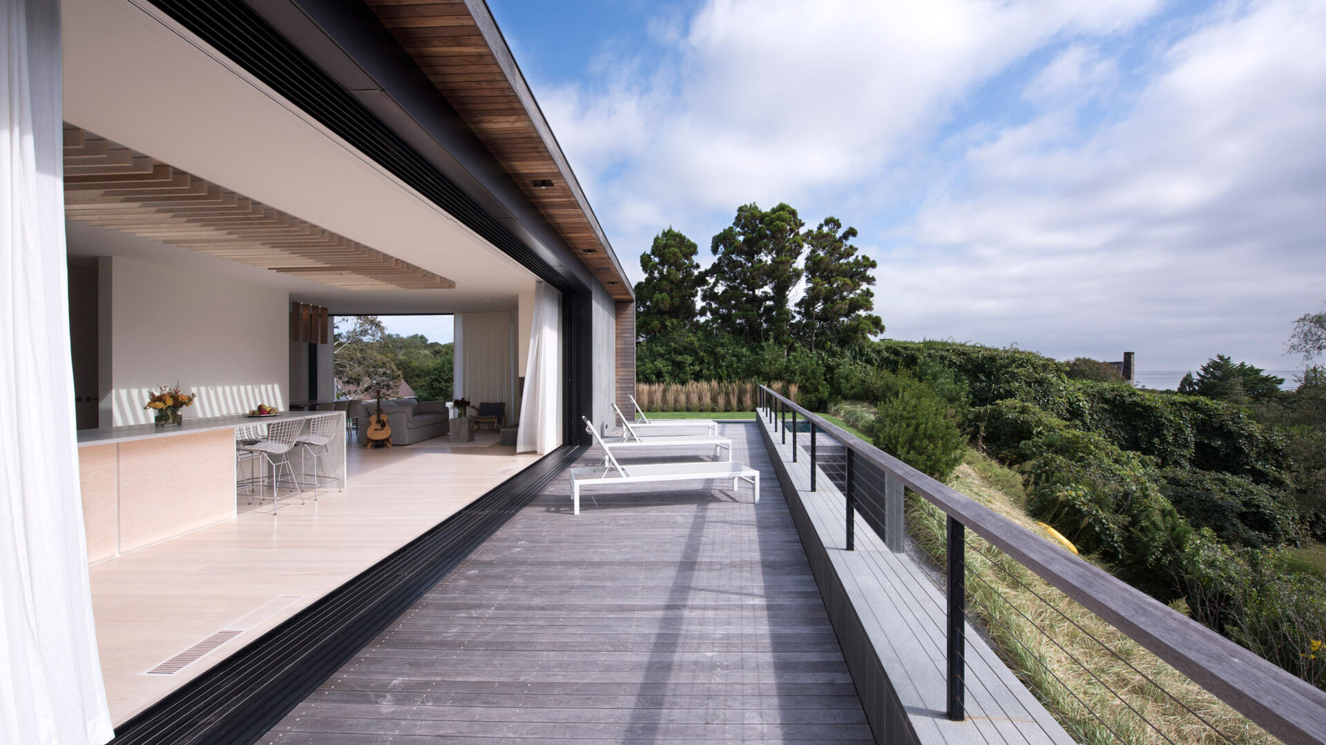 Una enorme pared de vidrio retráctil se abre al espacio habitable y ofrece vistas al mar, aire fresco y luz solar, difuminando la línea entre el interior y el exterior.