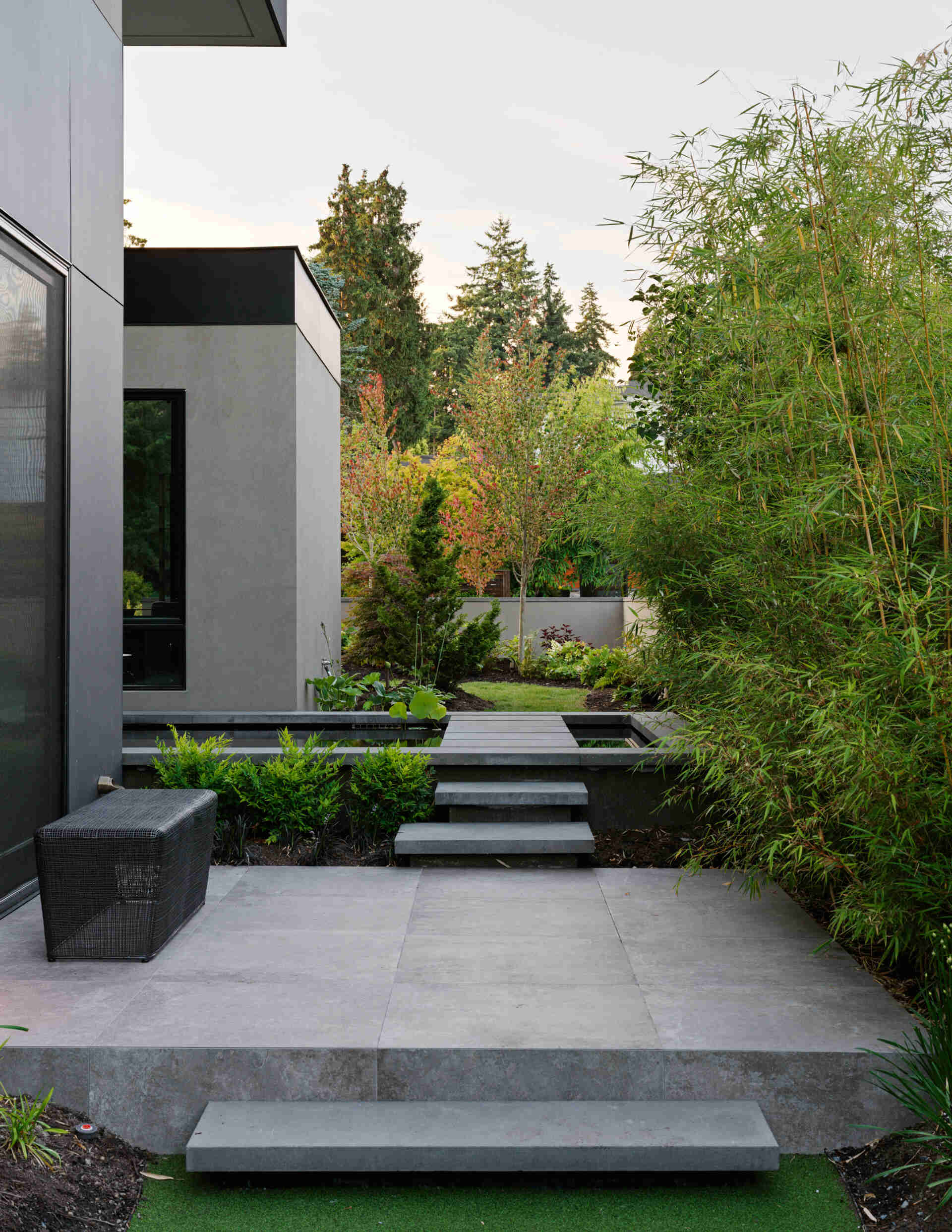 A reflecting pool and bamboo groves create a serene entrance, with thoughtful landscaping bringing nature close to the home.