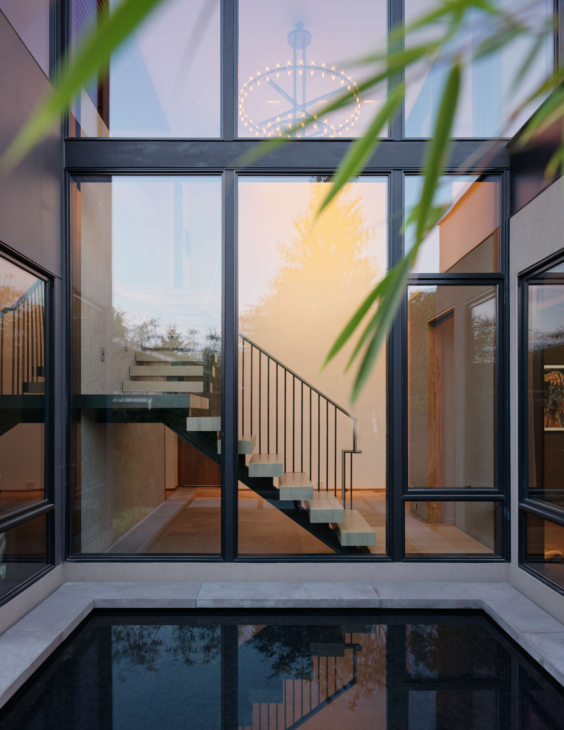 A reflecting pool and bamboo groves create a serene entrance, with thoughtful landscaping bringing nature close to the home.