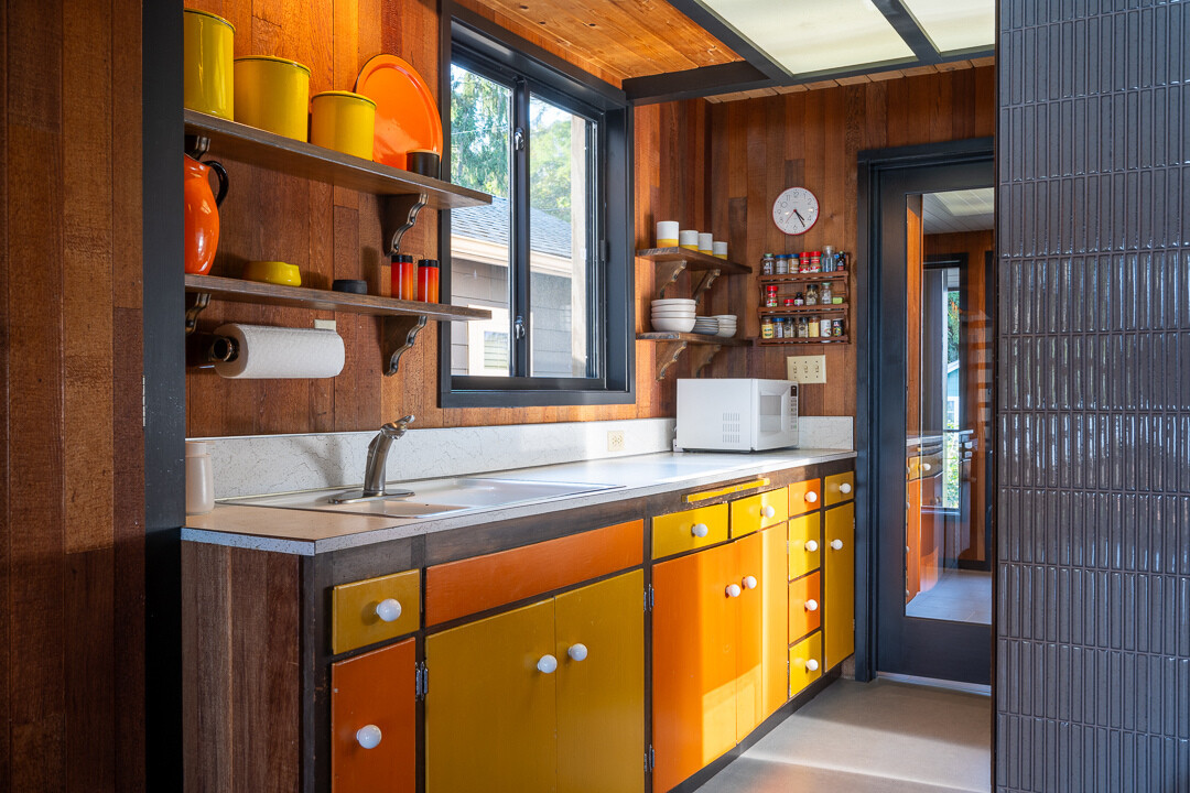 Se conservaron los coloridos gabinetes de cocina originales, lo que refleja el estilo moderno de mediados de siglo de la cabaña original.