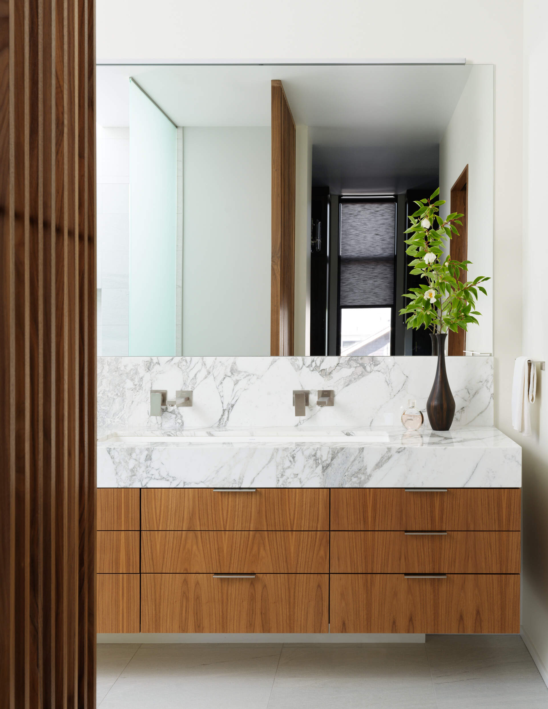 This primary bathroom suite has layered wood screens and minimalist textures to create calm.