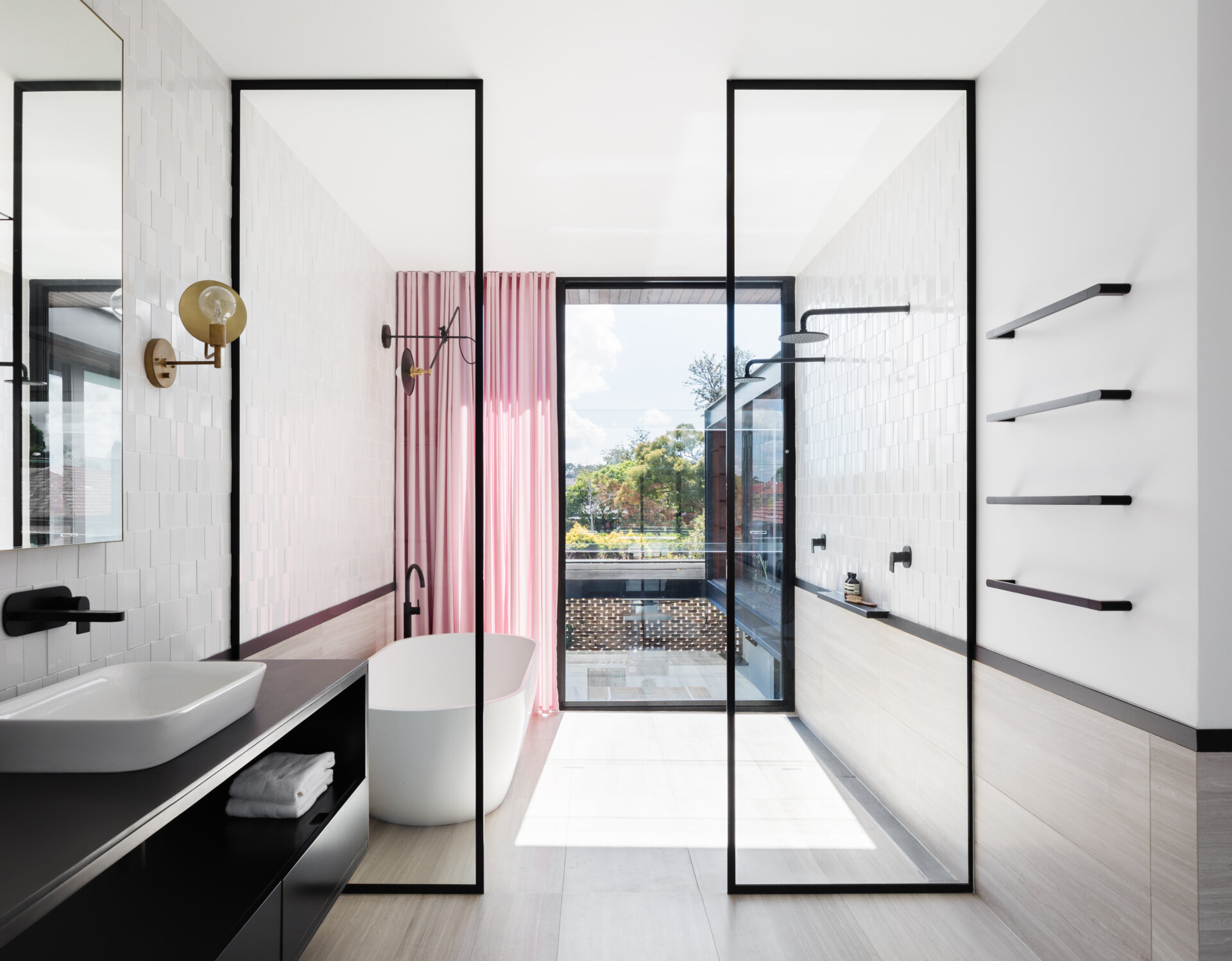 Black-framed glass and soft pink curtains add contrast and warmth to the master bathroom.