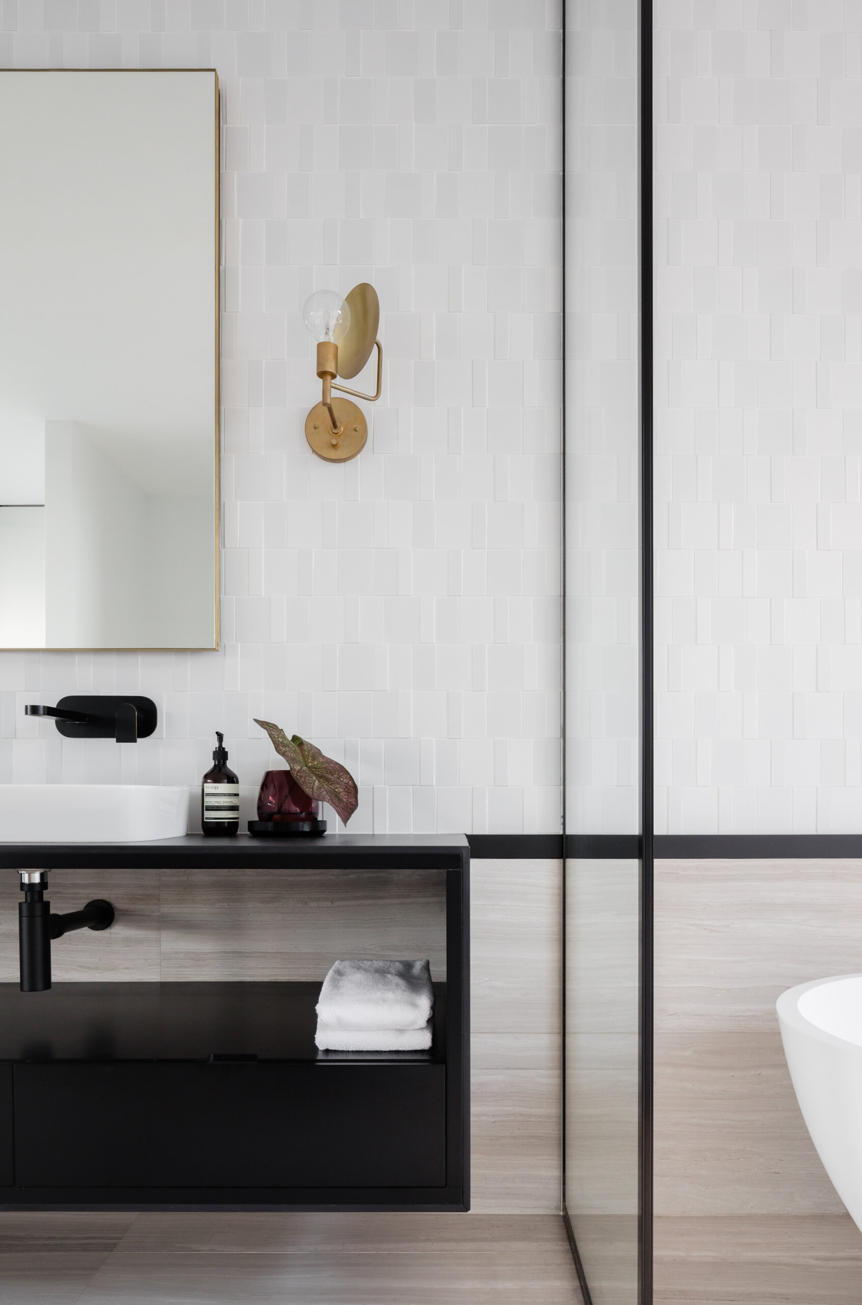 Black-framed glass and soft pink curtains add contrast and warmth to the master bathroom.