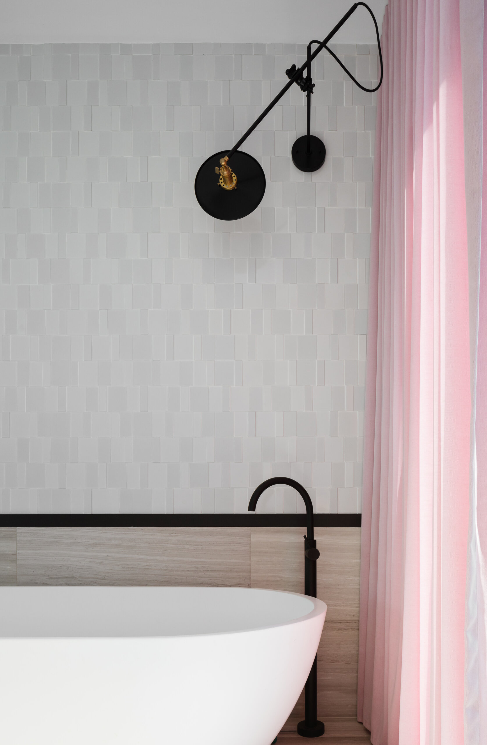 Black-framed glass and soft pink curtains add contrast and warmth to the master bathroom.