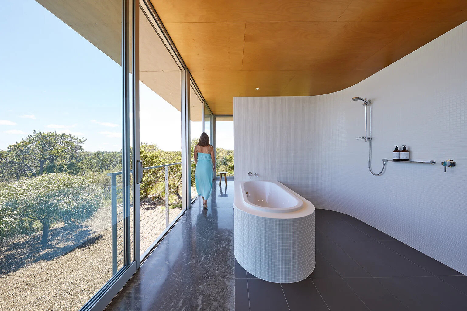 Curved mosaic walls and north-facing sliding doors bring winter sun into the bathroom.