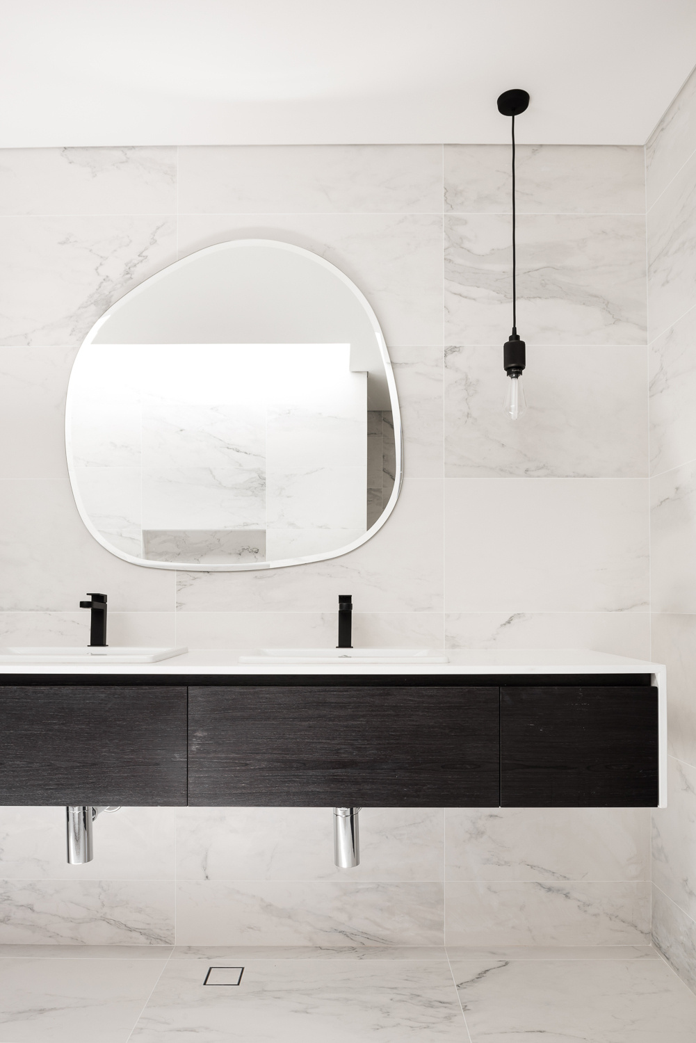A freestanding bath beneath a skylight and a dark timber vanity create a calm, light-filled bathroom space.