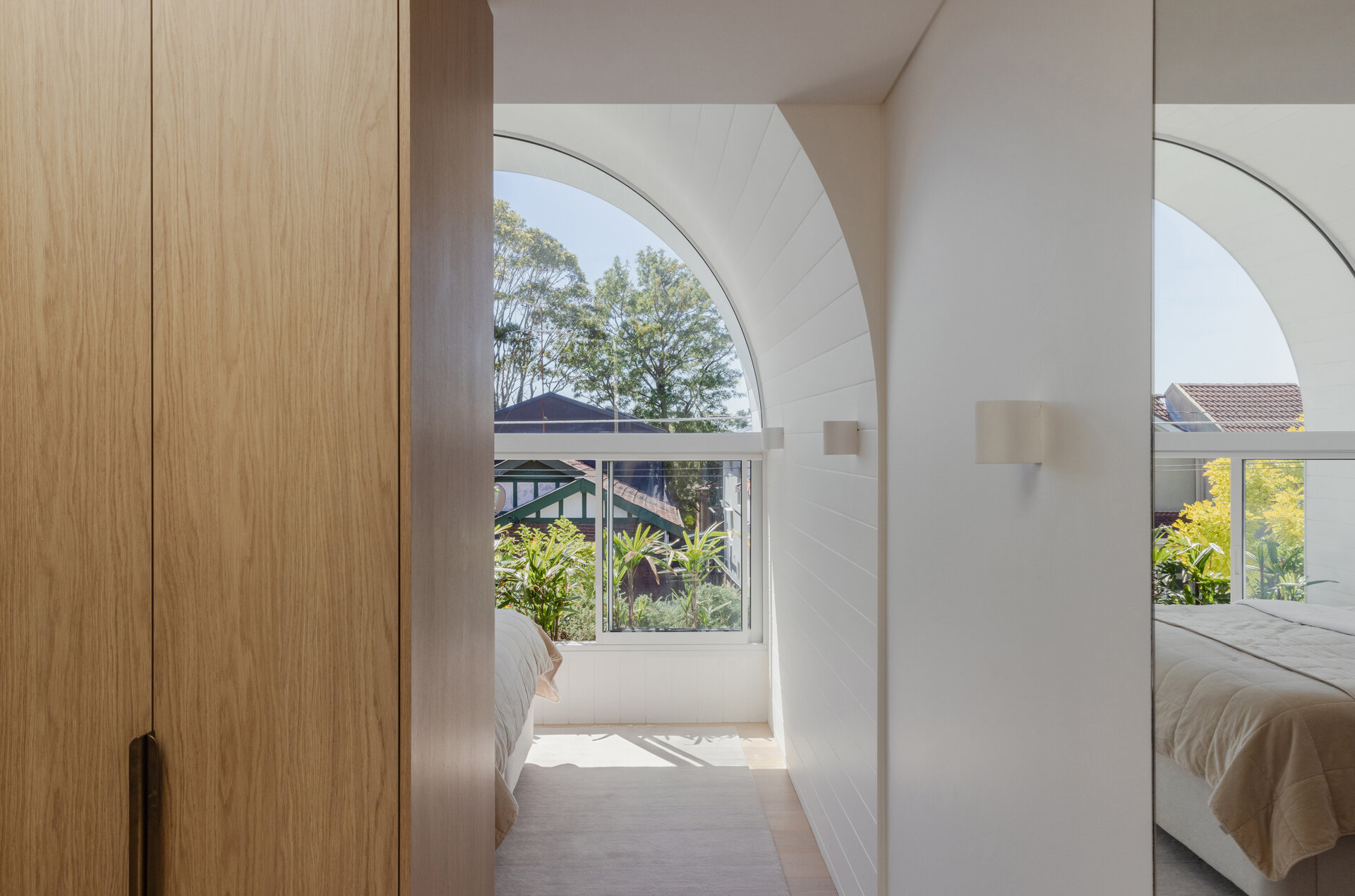 A modern white bedroom with an arched window.
