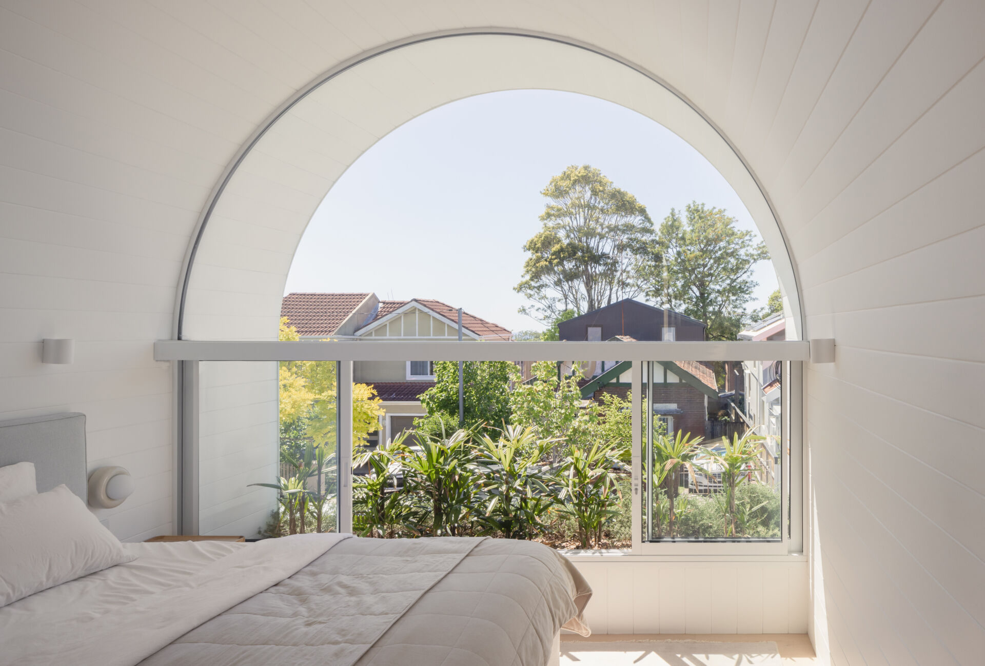A modern white bedroom with an arched window.