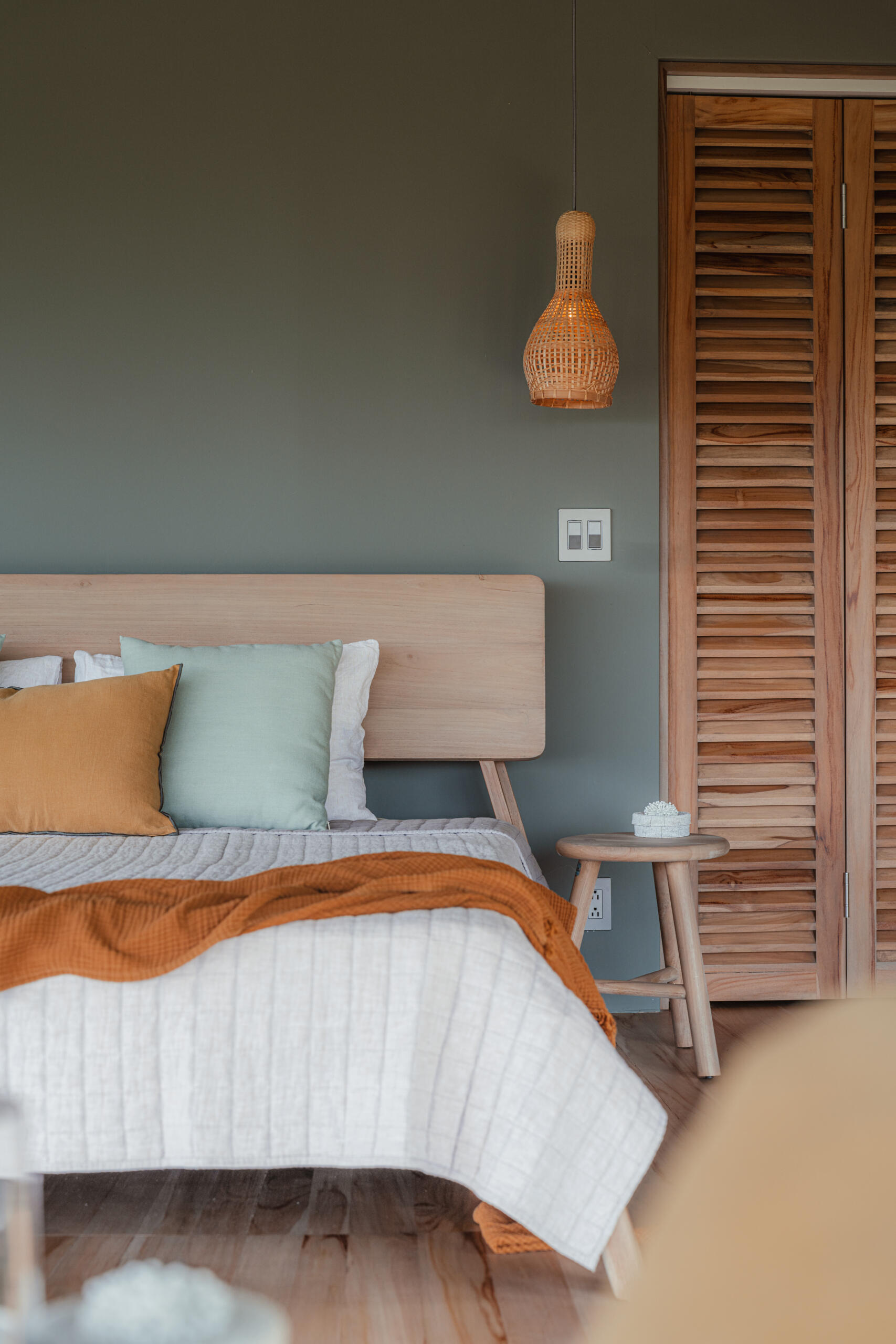 A curved open air bedroom where the sweeping roofline and angled supports frame uninterrupted views of forest and ocean. The low timber bed and minimal furnishings keep the focus on light, air, and landscape.