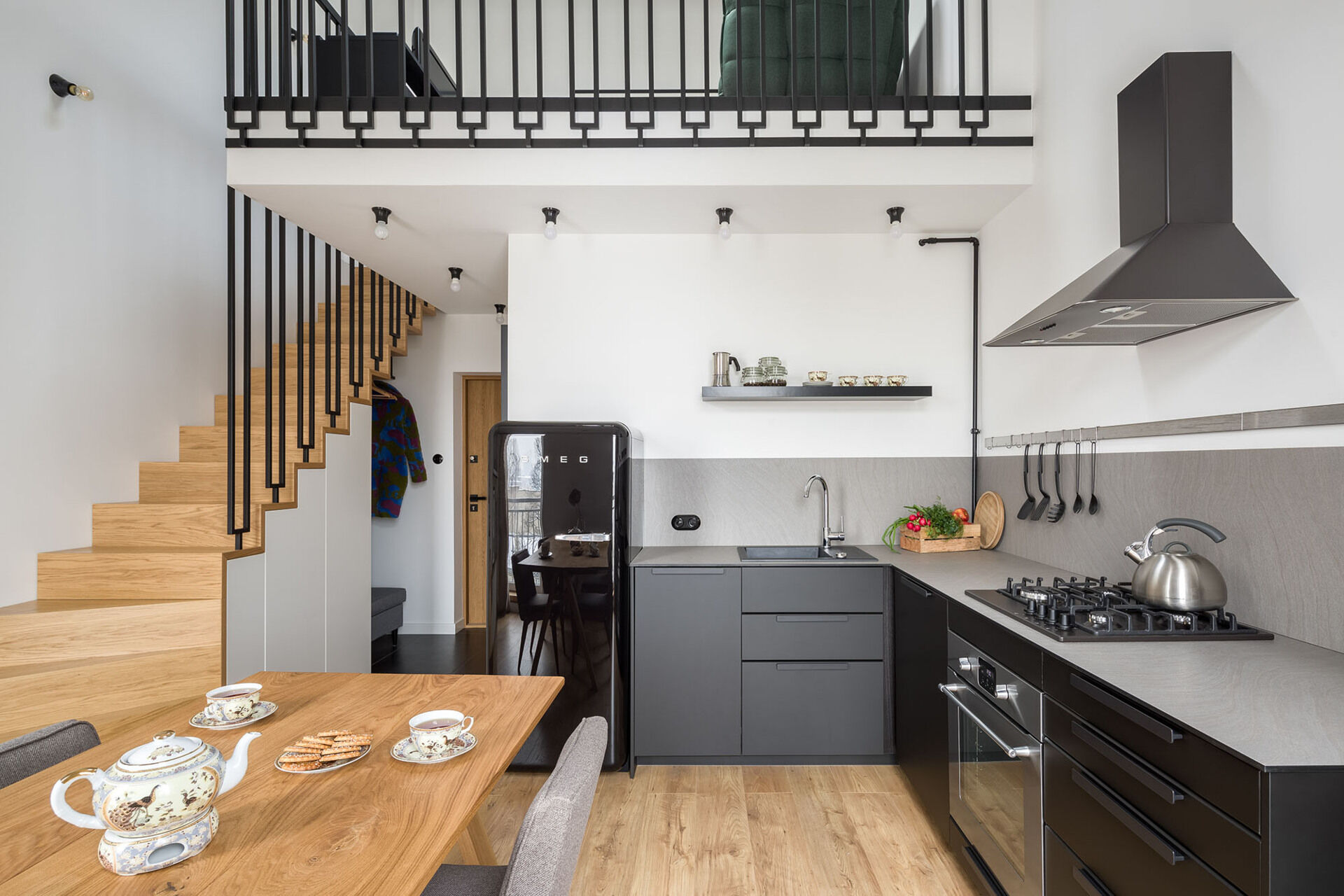 Matte black kitchen cabinets and a grey countertop create a sleek look in this open plan apartment.
