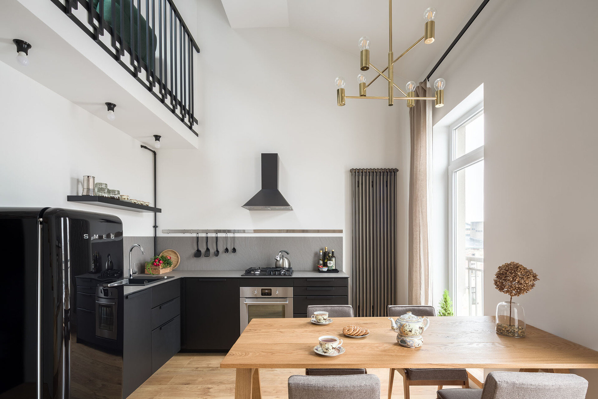 Matte black kitchen cabinets and a grey countertop create a sleek look in this open plan apartment.