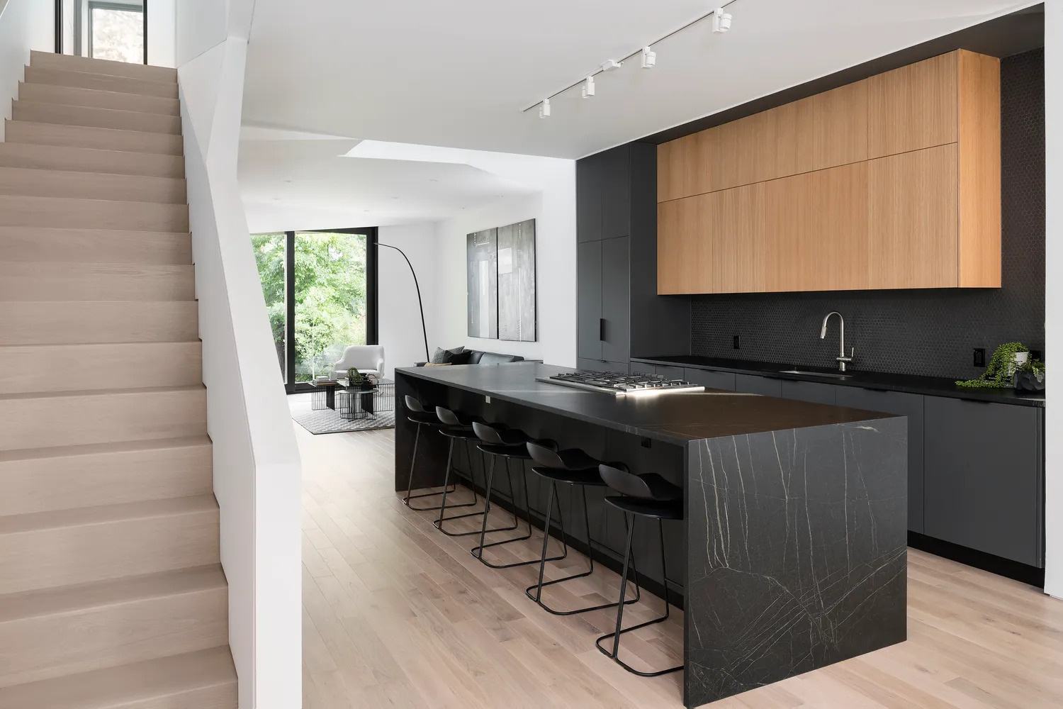 Matte black kitchen cabinets and island take centre stage inside a calm white interior, adding depth and drama without overwhelming the space.