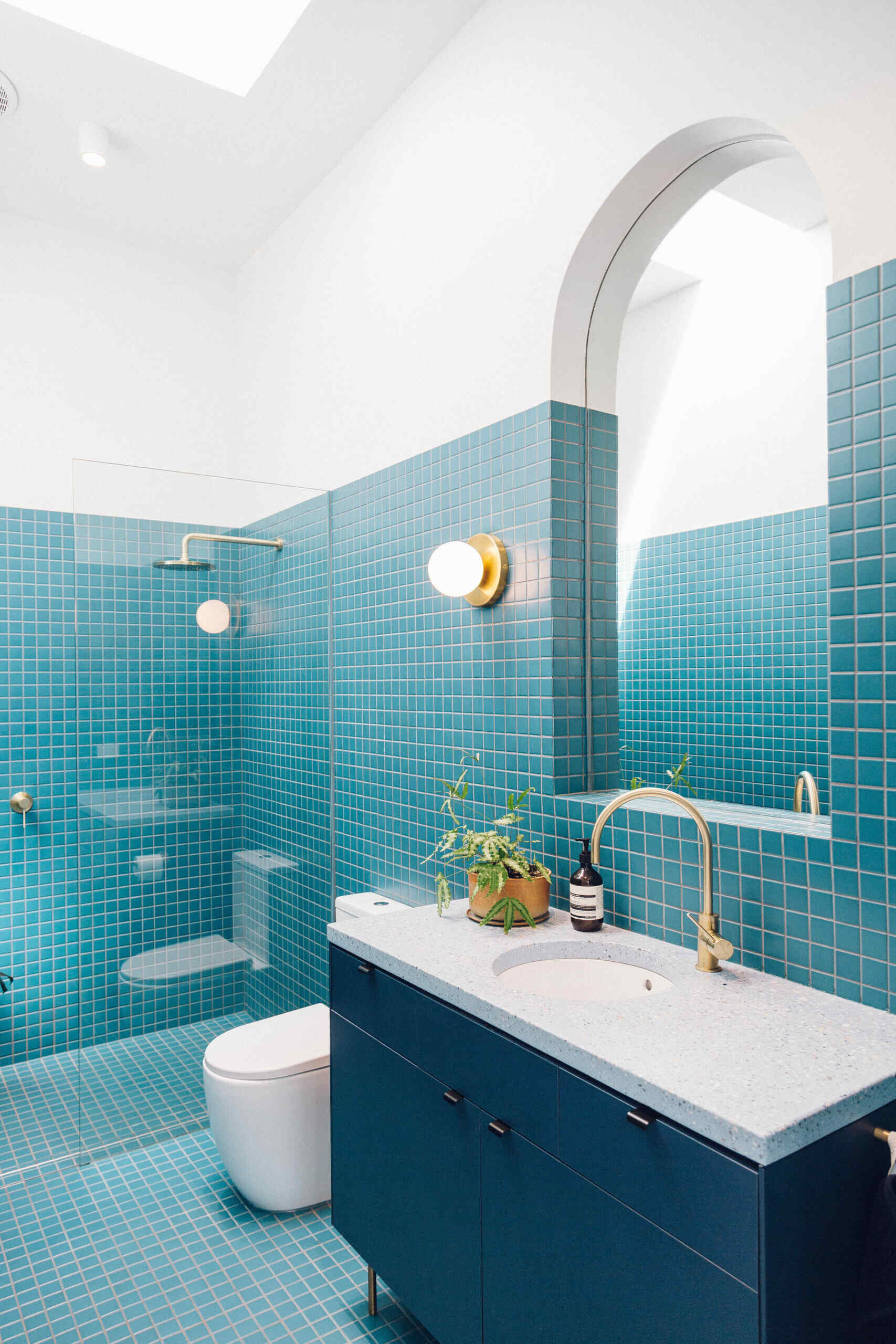 Bright blue tiles, a skylight, and a curved mirror bring colour and fun into the expanded bathroom.