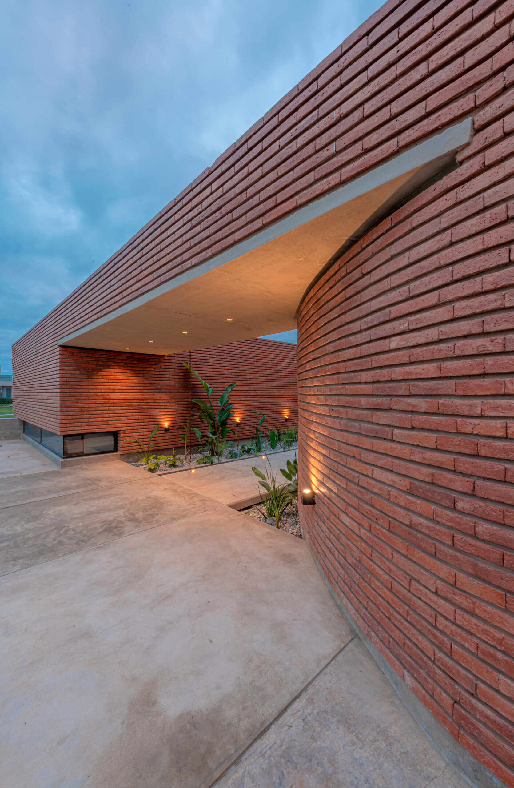 A considered entry sequence where water and garden elements guide movement, turning arrival into a calm, intentional experience within this brick family house in Córdoba.