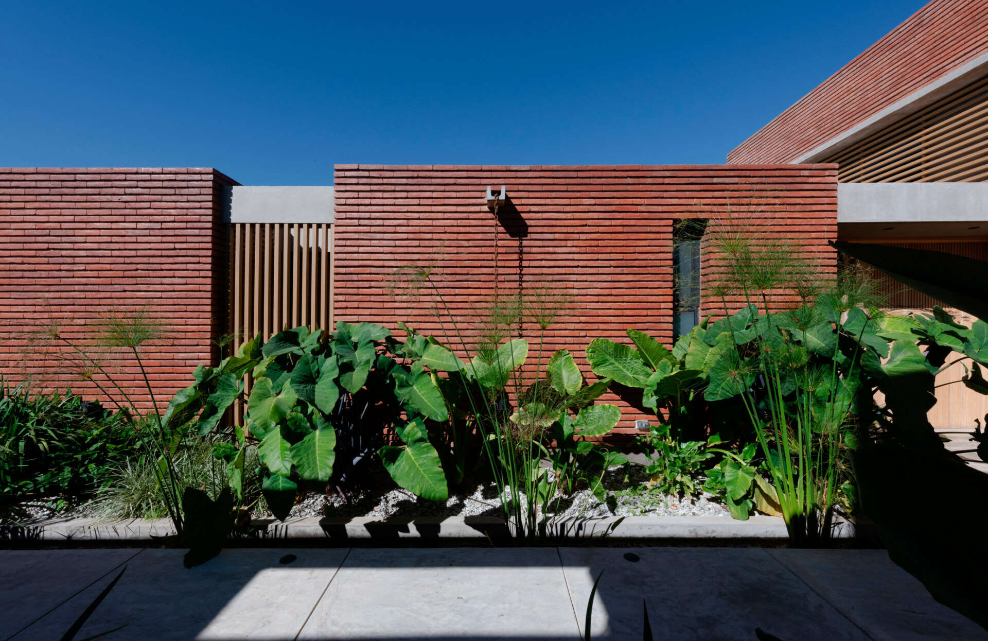 A considered entry sequence where water and garden elements guide movement, turning arrival into a calm, intentional experience within this brick family house in Córdoba.