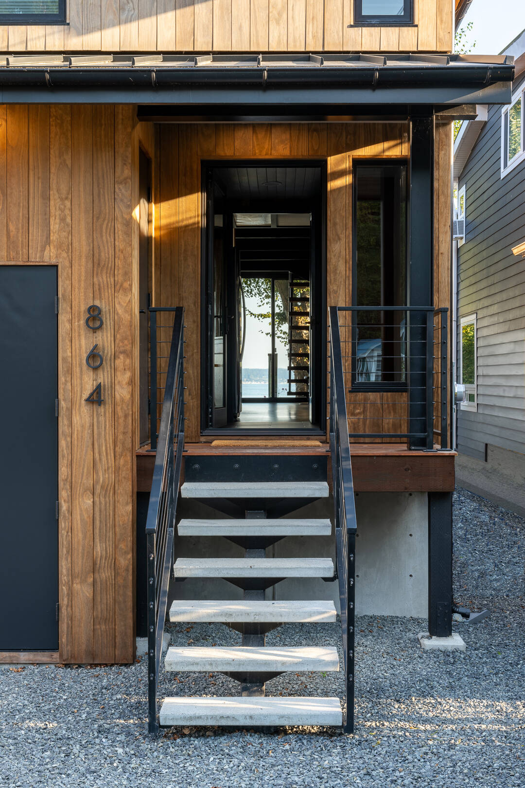 Elevar la cabina requiere un nuevo método de entrada. Se añadió una escalera de hormigón y acero para complementar la estética de mediados de siglo y al mismo tiempo resistir las condiciones de inundación. El diseño equilibra la durabilidad y las líneas limpias, creando una entrada acogedora que combina con el estilo de la casa actualizada.