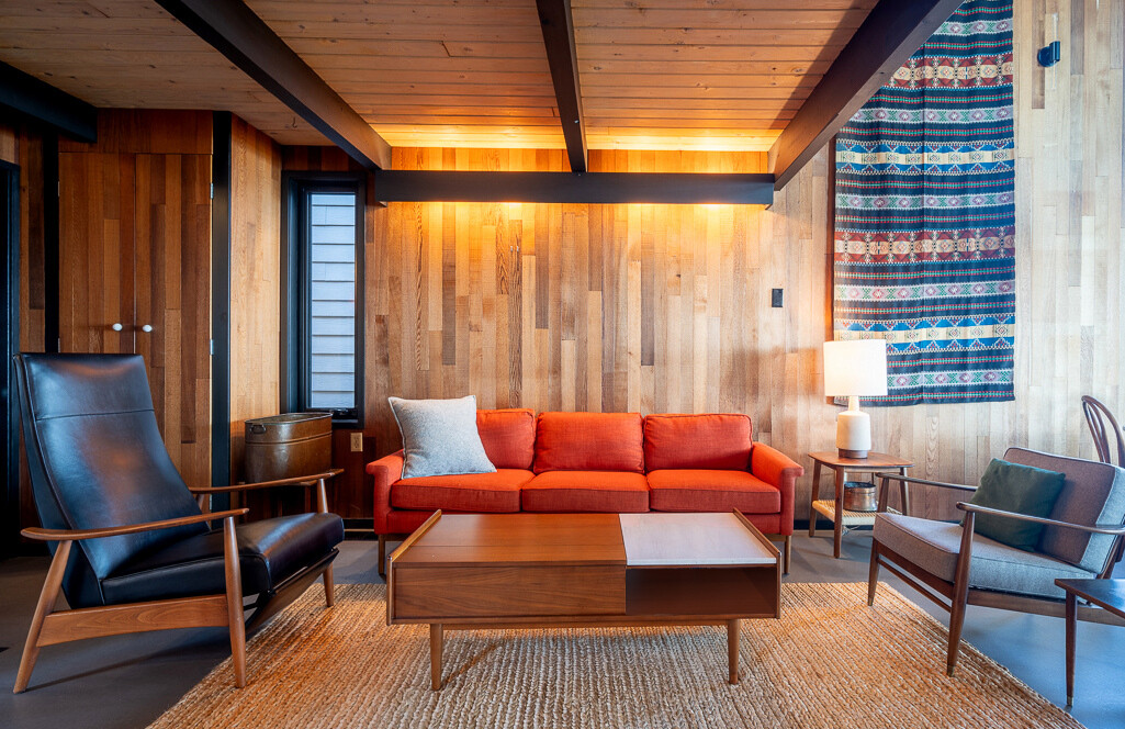 La eliminación de la chimenea de ladrillo original permitió elevar la casa. En su lugar hay una chimenea flotante de estilo medieval apoyada contra una pared de azulejos. La gran sala, donde se encuentra la sala de estar, se siente más luminosa y relajada, enfatizando la apertura y la conexión con el exterior.