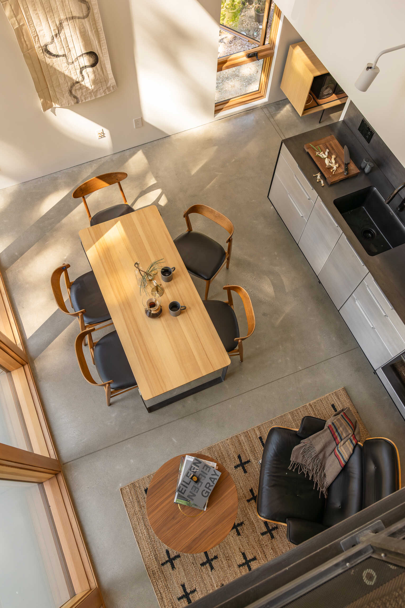 The middle level is organized as a single open room that brings together the living, dining, and kitchen areas, along with a full bathroom. This floor functions as the social heart of the cabin, where daily life unfolds around shared space rather than separate rooms.