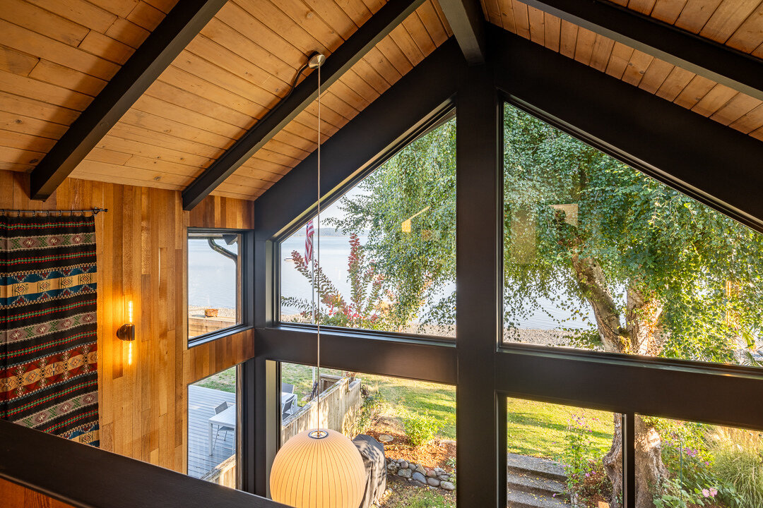 Un loft con estructura de abeto se encuentra encima de la gran sala, aportando calidez e interés arquitectónico. La estructura de planta abierta alberga una sala de estar secundaria que complementa la escalera flotante y mantiene la sensación de luminosidad y amplitud del espacio principal.