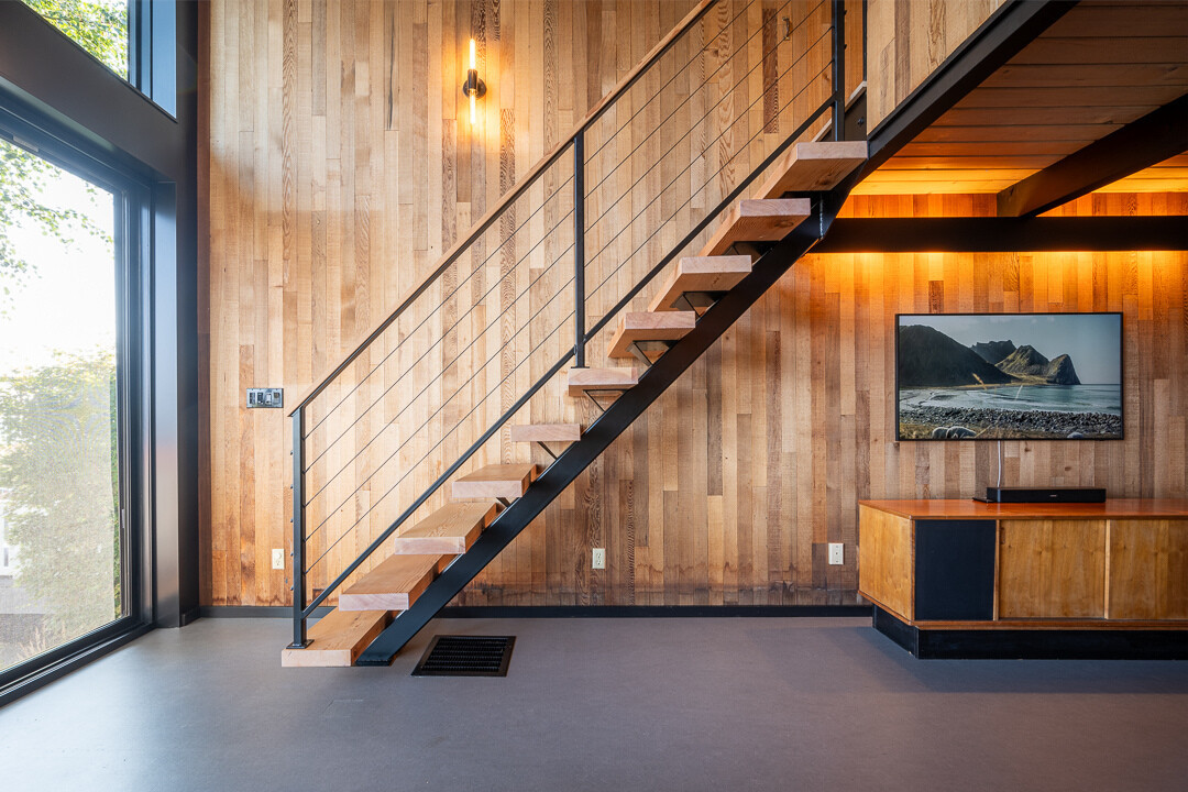 La pesada escalera de madera original fue reemplazada por un larguero central de acero y peldaños flotantes con barandillas de cable. El nuevo diseño reduce el impacto visual en el paisaje y realza la estética moderna de mediados de siglo.