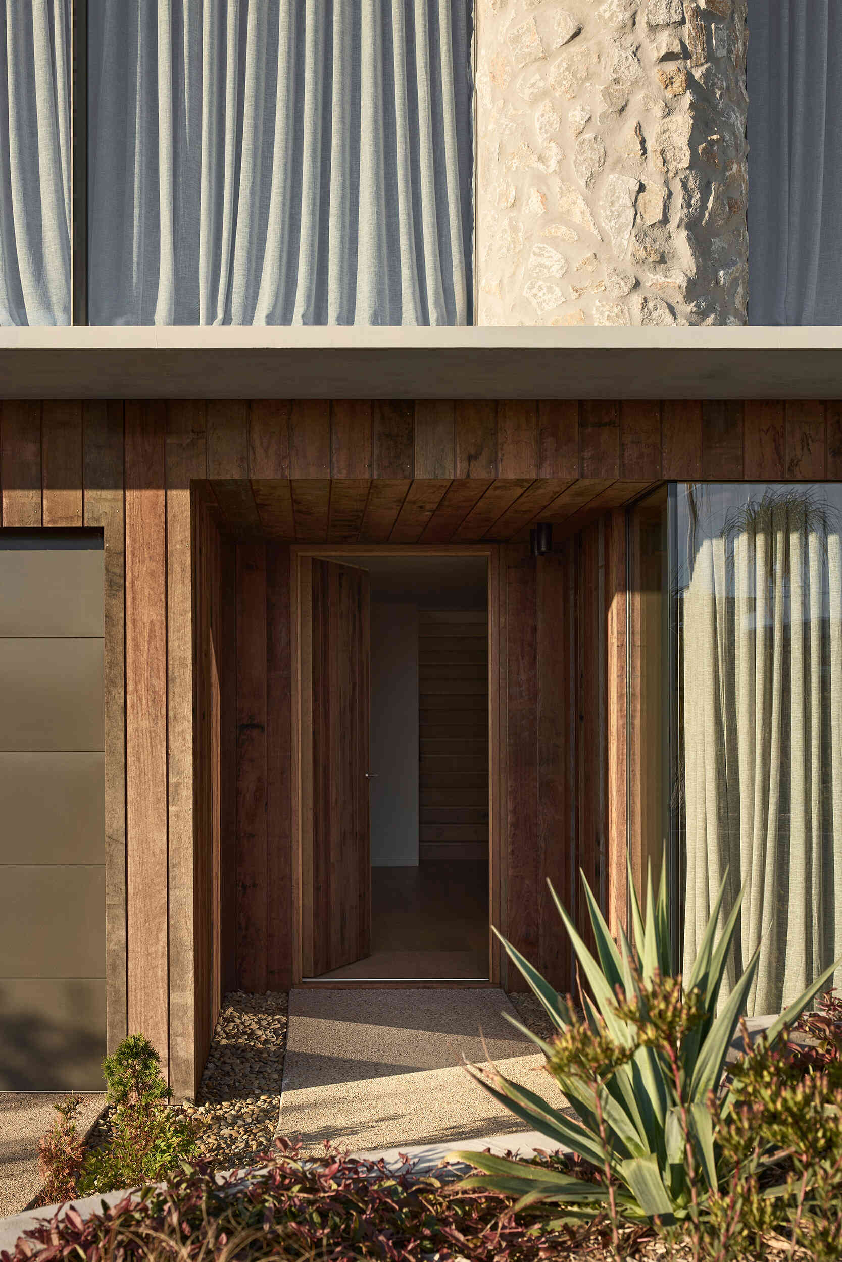 Recycled timber, concrete, limestone, and copper define a coastal home built to weather and remain refined over time.