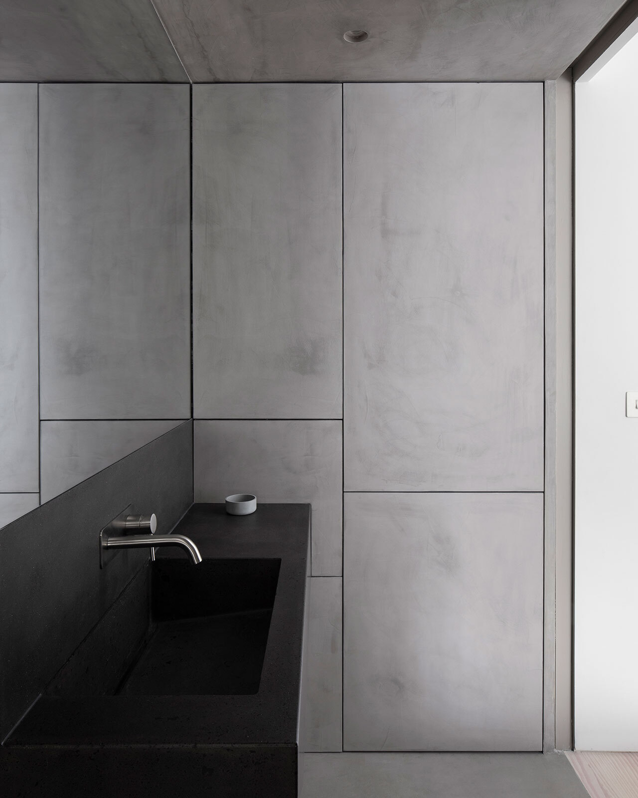 Ensuites feature seamless microcement on walls, floors, ceilings, and cabinetry, paired with bespoke concrete vanities and brushed stainless steel fixtures.