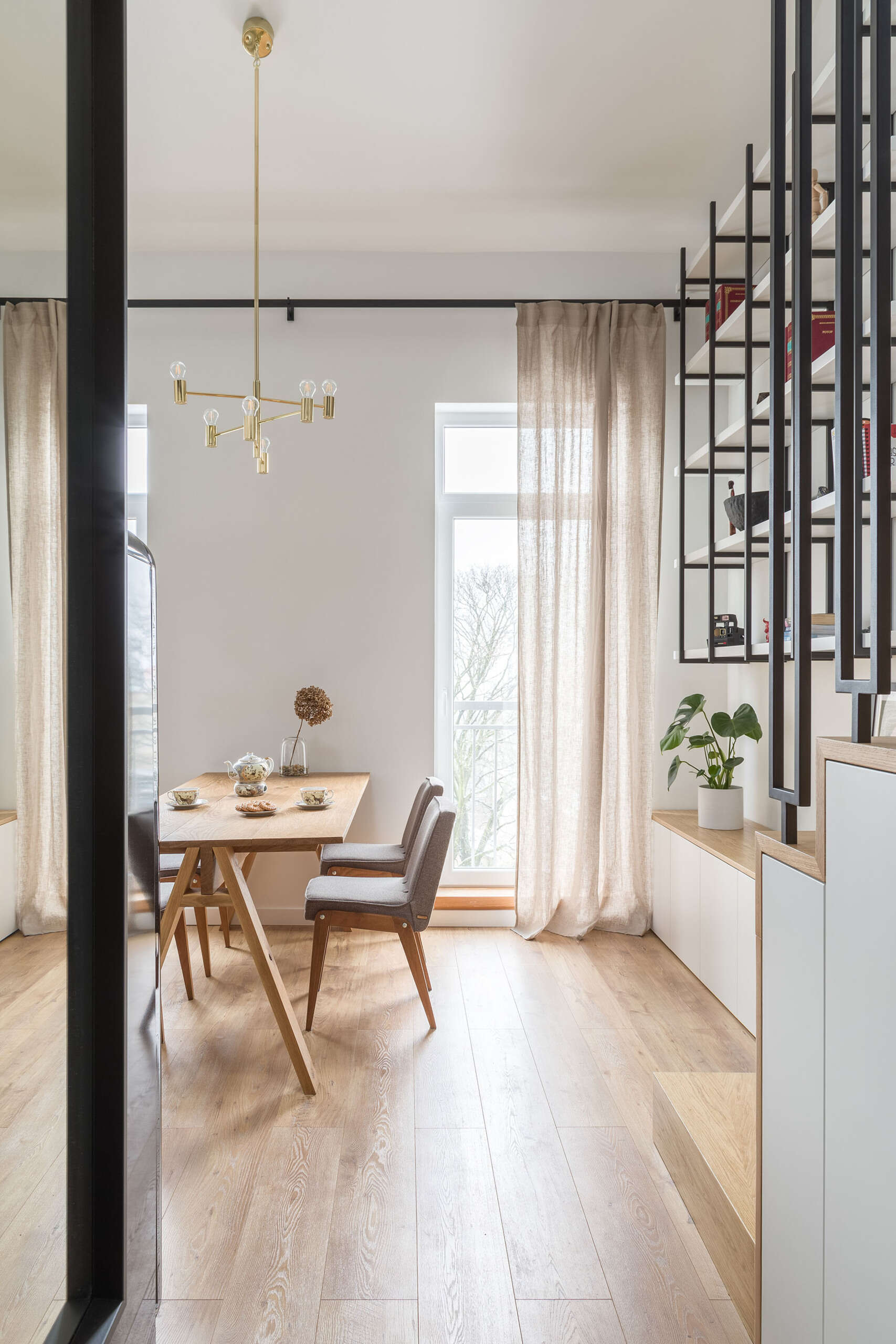A solid oak dining table and minimalist chandelier anchor the open plan layout and highlight ceiling height.