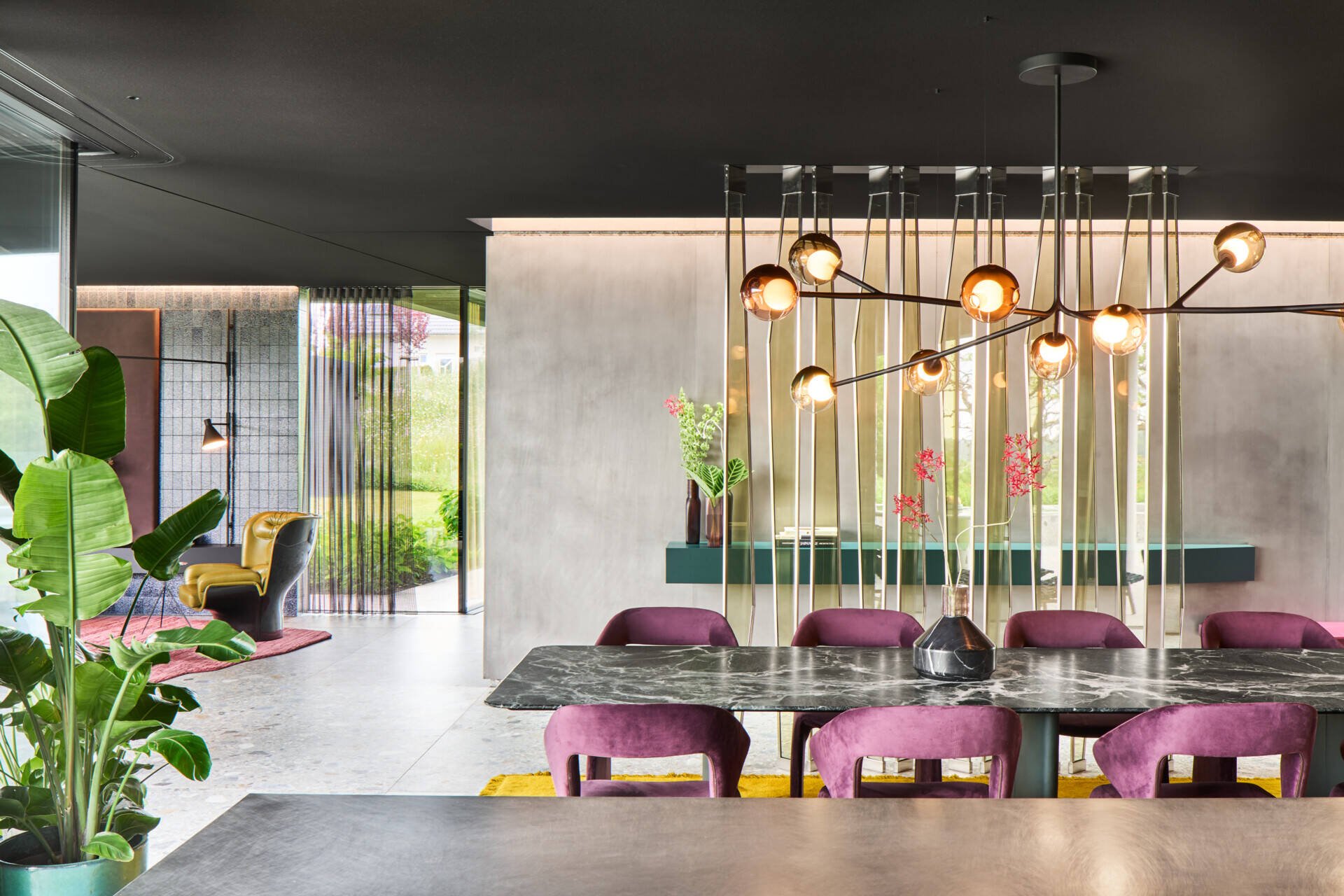 This dining space balances soft elegance with a little sparkle. A smoky-glass globe chandelier stretches above the stone table top, while plush plum velvet chairs add rich texture and comfort.