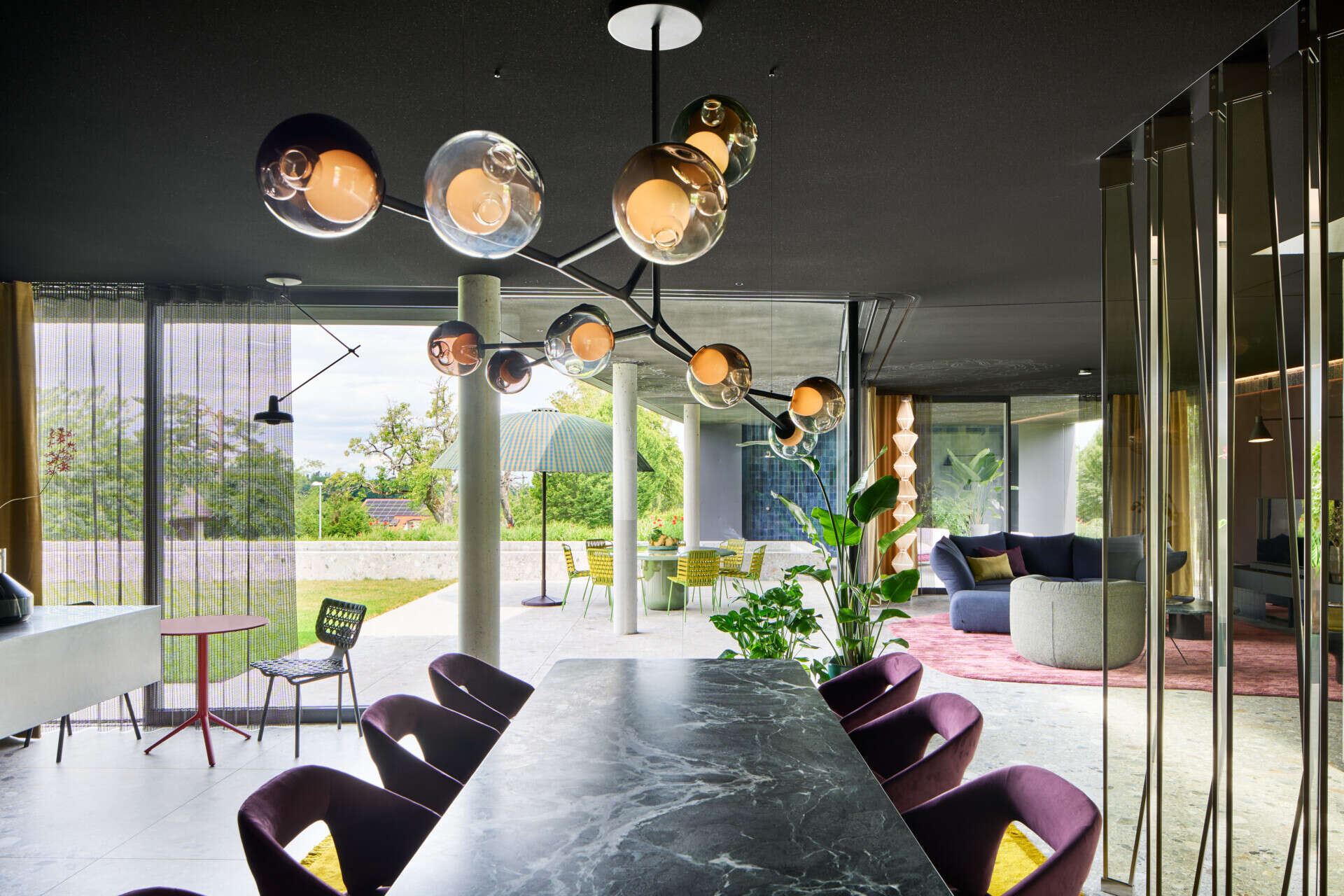 This dining space balances soft elegance with a little sparkle. A smoky-glass globe chandelier stretches above the stone table top, while plush plum velvet chairs add rich texture and comfort.