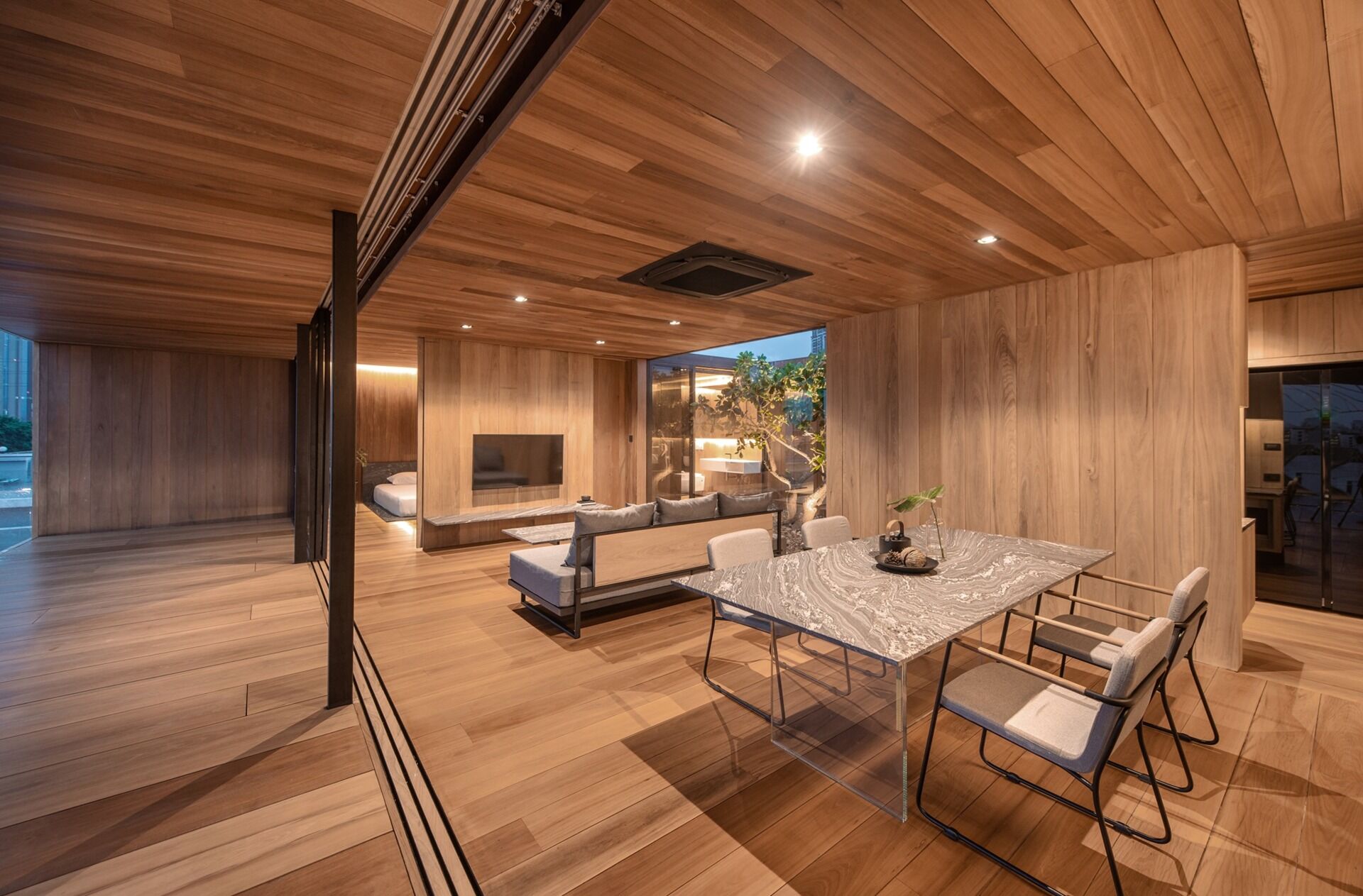 An open plan living and dining space wrapped in wood and glass frames panoramic views of the surrounding city.