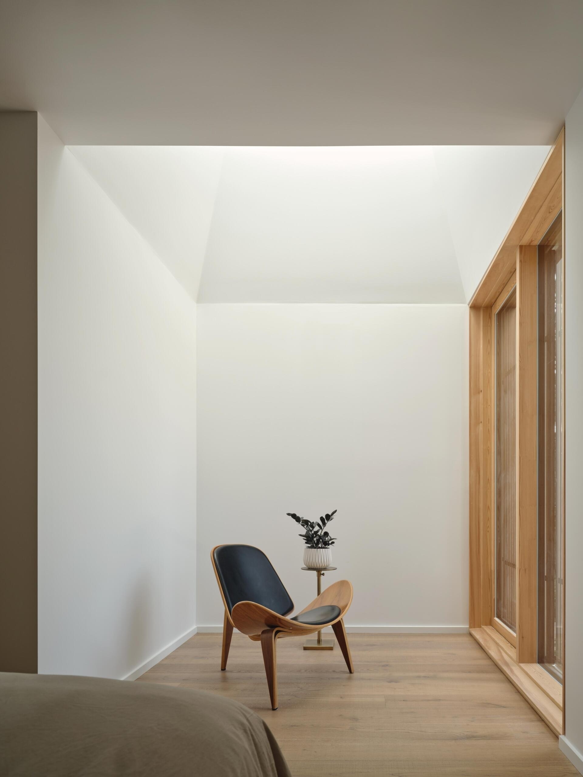 The guest bedroom is compact, with a sitting area tucked beneath a pyramidal ceiling. The geometry creates a sense of enclosure while maintaining visual interest.