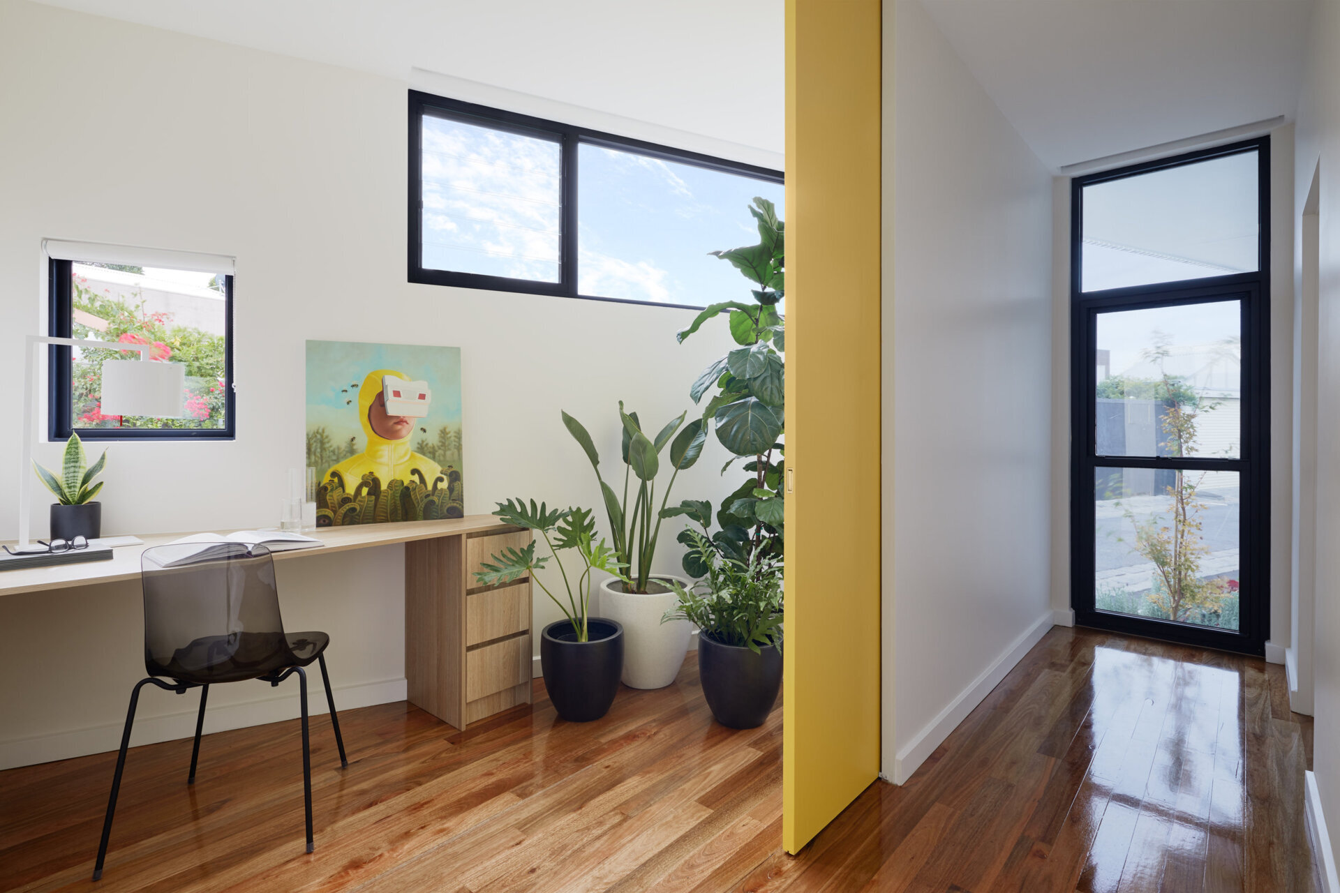 The home office fits neatly into a small angled corner, while hallway sightlines connect the interior to the garden beyond.