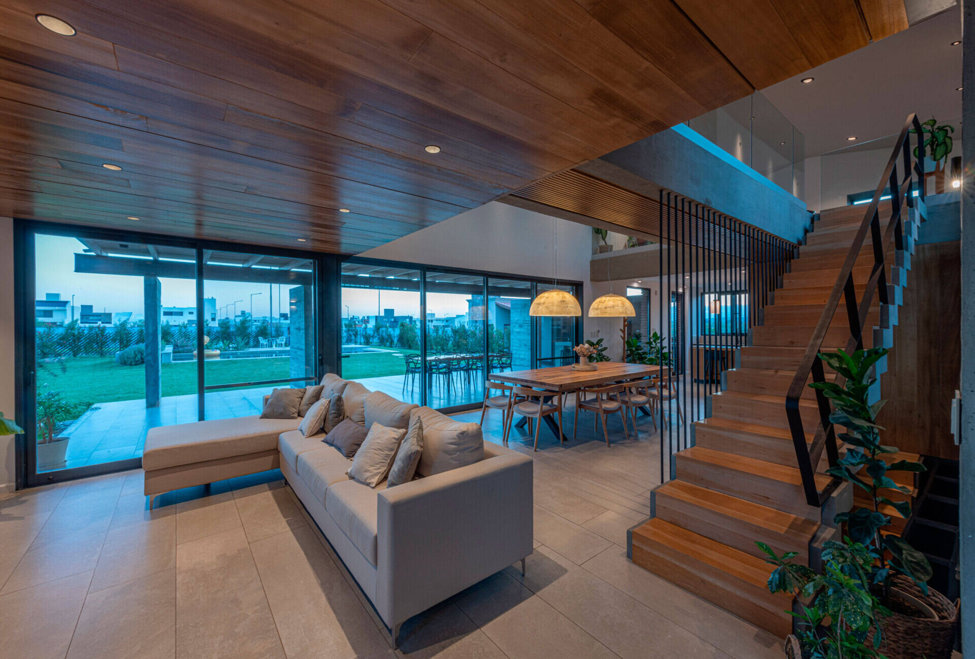 Inside, the living room forms part of the open social space, alongside the dining area and kitchen. A double-height window opens to the north, overlooking the entrance courtyard and drawing in sunlight throughout the day.