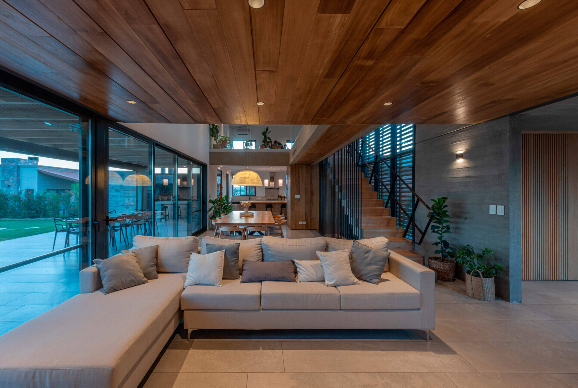 Inside, the living room forms part of the open social space, alongside the dining area and kitchen. A double-height window opens to the north, overlooking the entrance courtyard and drawing in sunlight throughout the day.