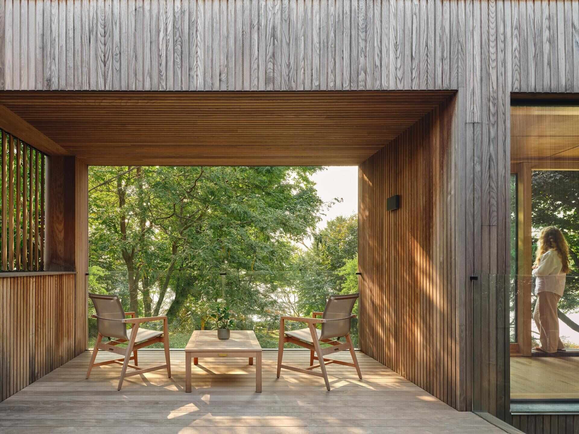 On the second floor of this modern home, the exterior deck includes both covered and open areas. It looks out toward Lake Ontario while remaining connected to the spaces beneath and above.