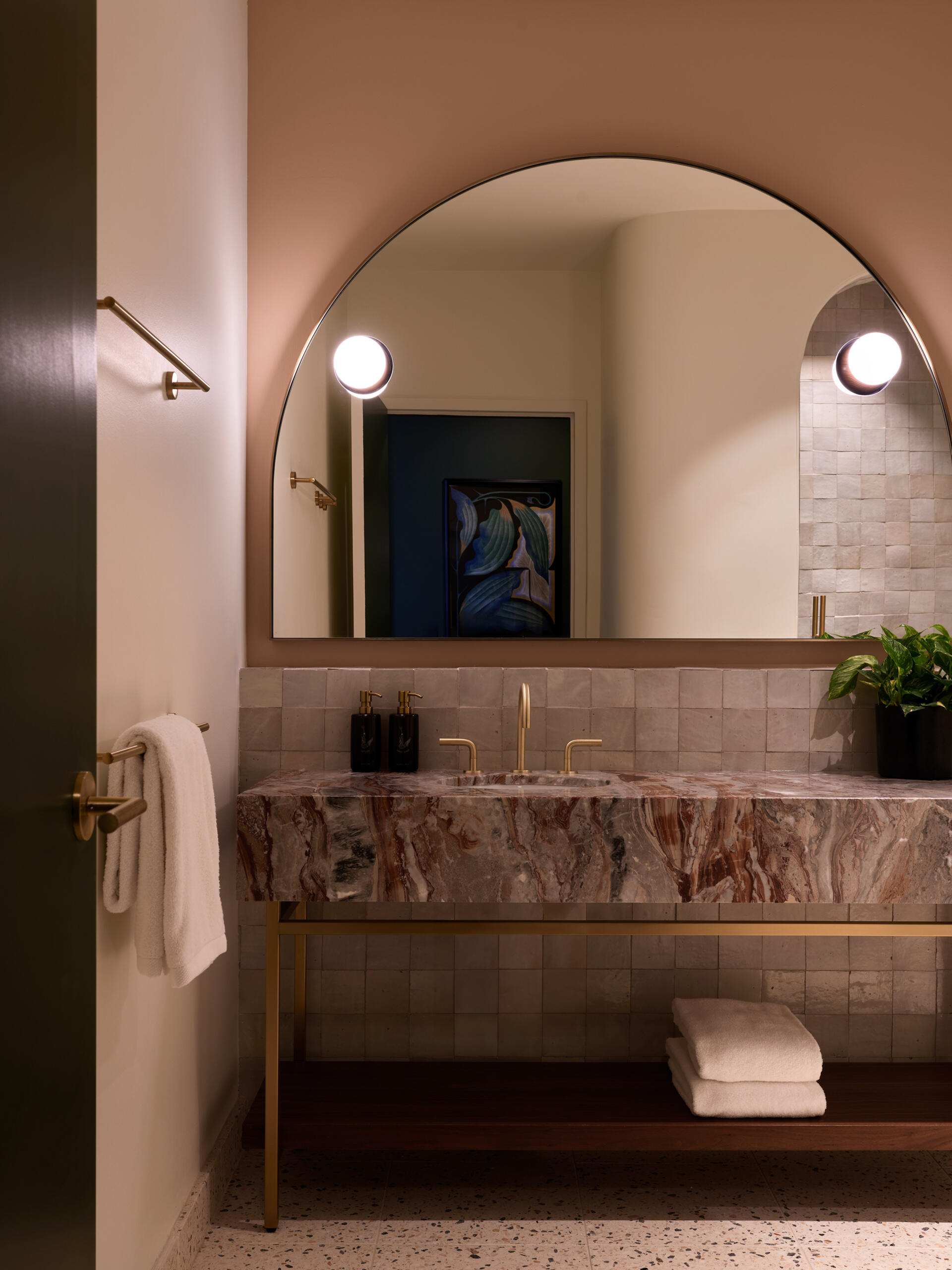 Hotel guest rooms and bathrooms blend Nordic modern influences with terrazzo floors, curved details, custom millwork, and integrated bar setups.