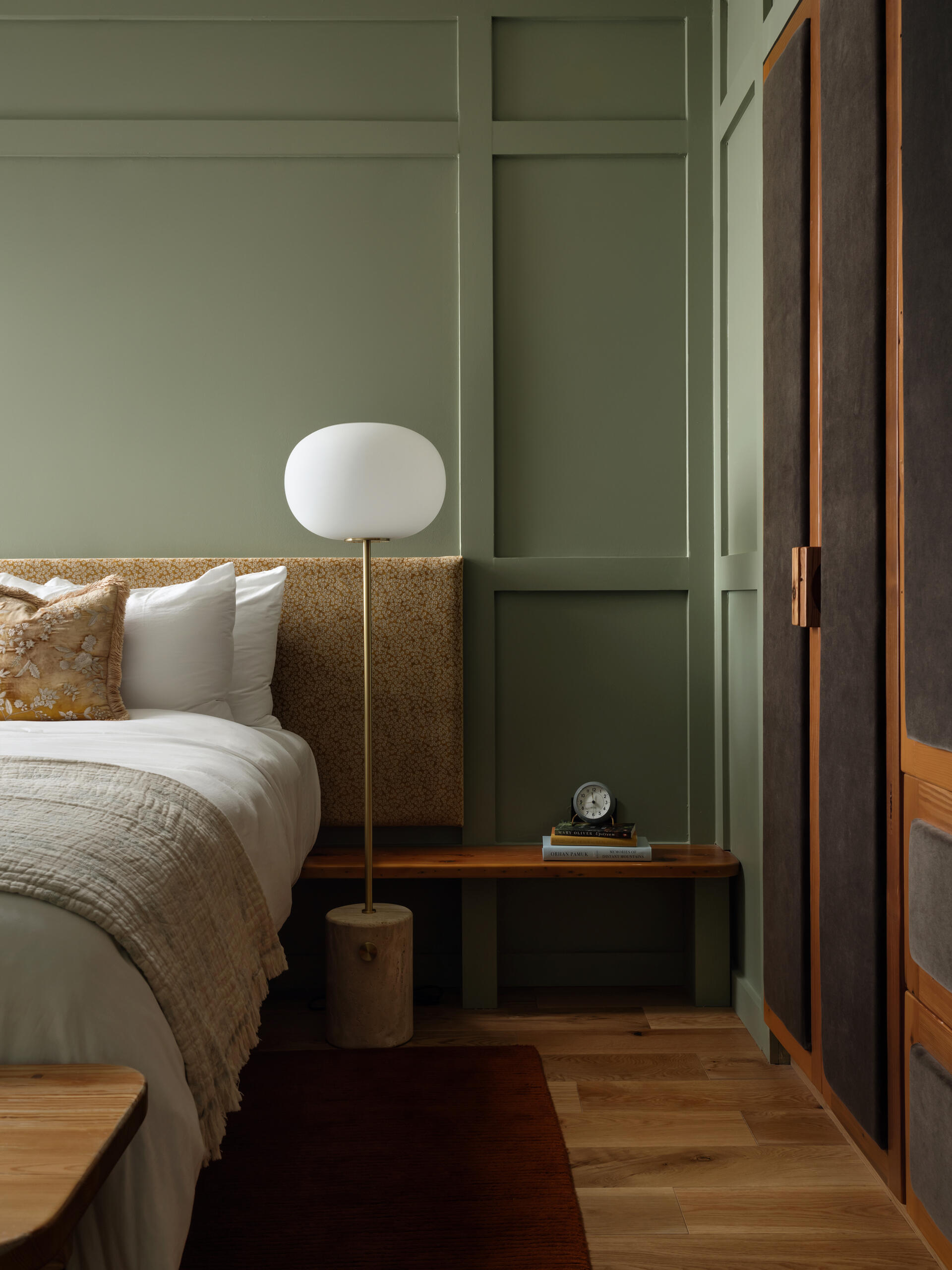 This modern hotel suites features muted green walls and matching tiles, warm timber floors, and restrained furnishings that prioritize calm, texture, and light.