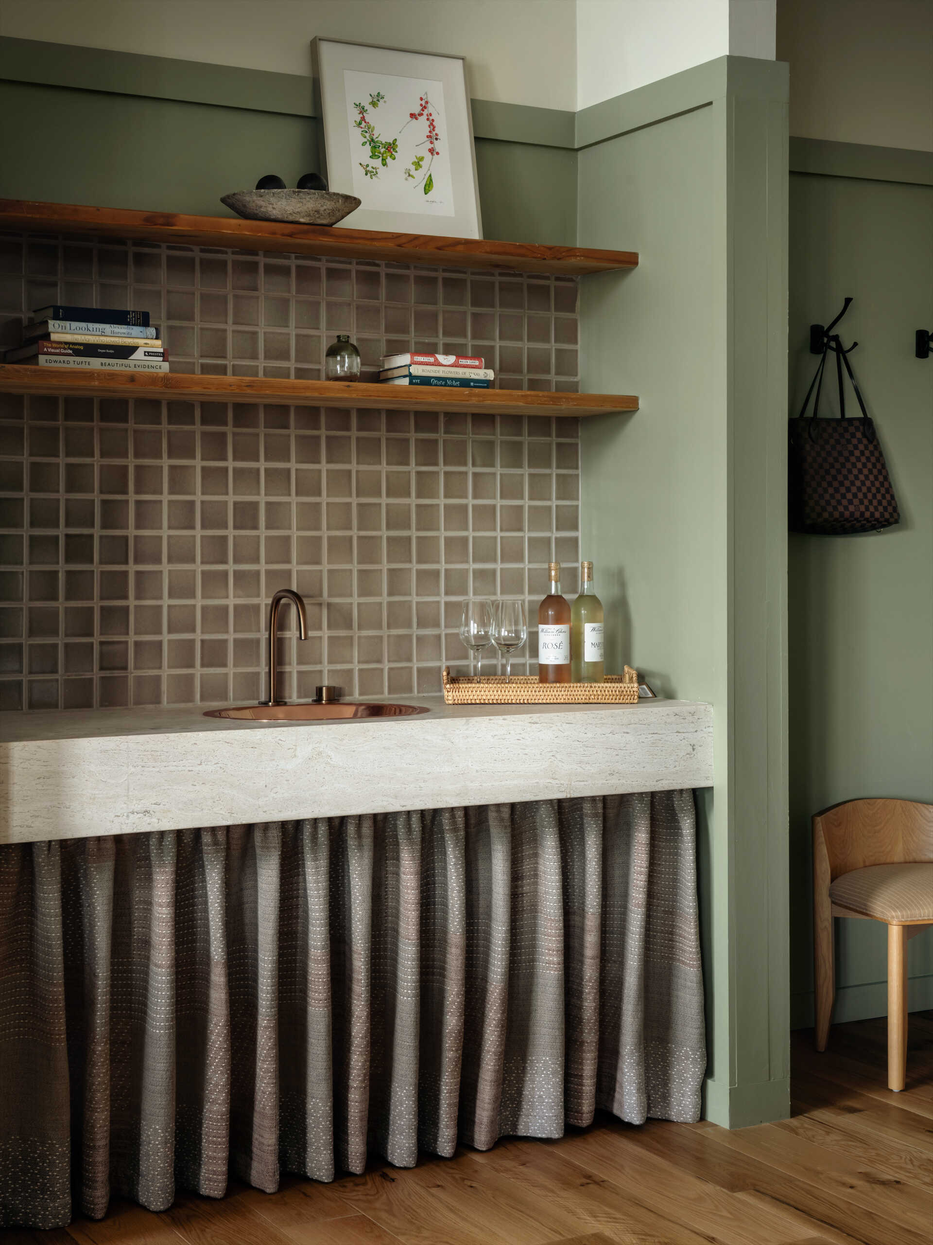 This modern hotel suites features muted green walls and matching tiles, warm timber floors, and restrained furnishings that prioritize calm, texture, and light.