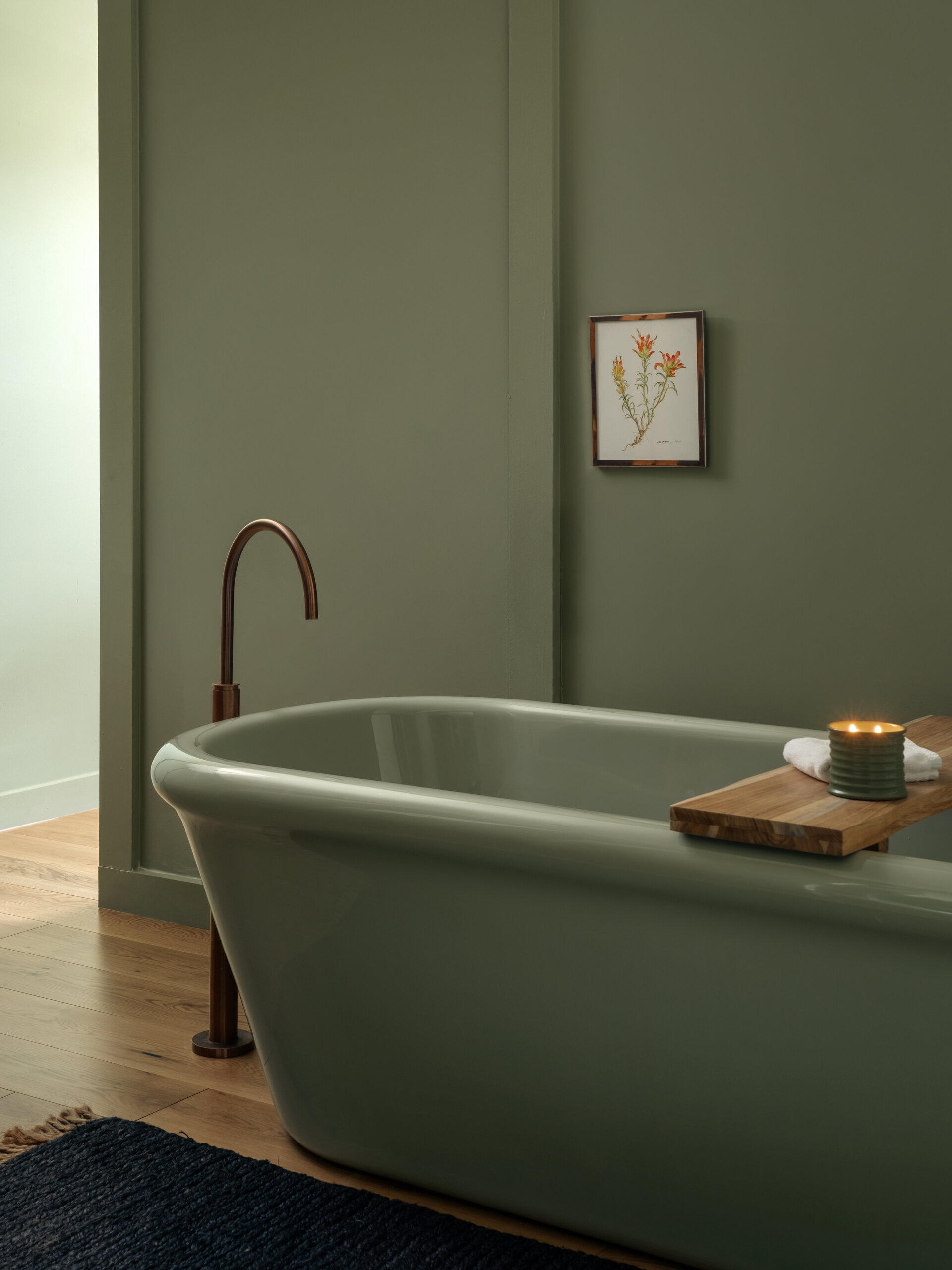 This modern hotel suites features muted green walls and matching tiles, warm timber floors, and restrained furnishings that prioritize calm, texture, and light.