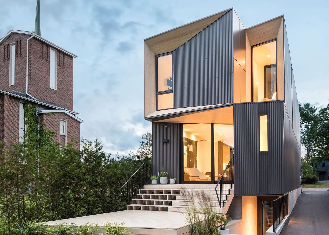 A striking modern home in Toronto defined by sharp angles, warm timber cladding, and dark steel siding. Tesseract House stands out through geometry and contrast.