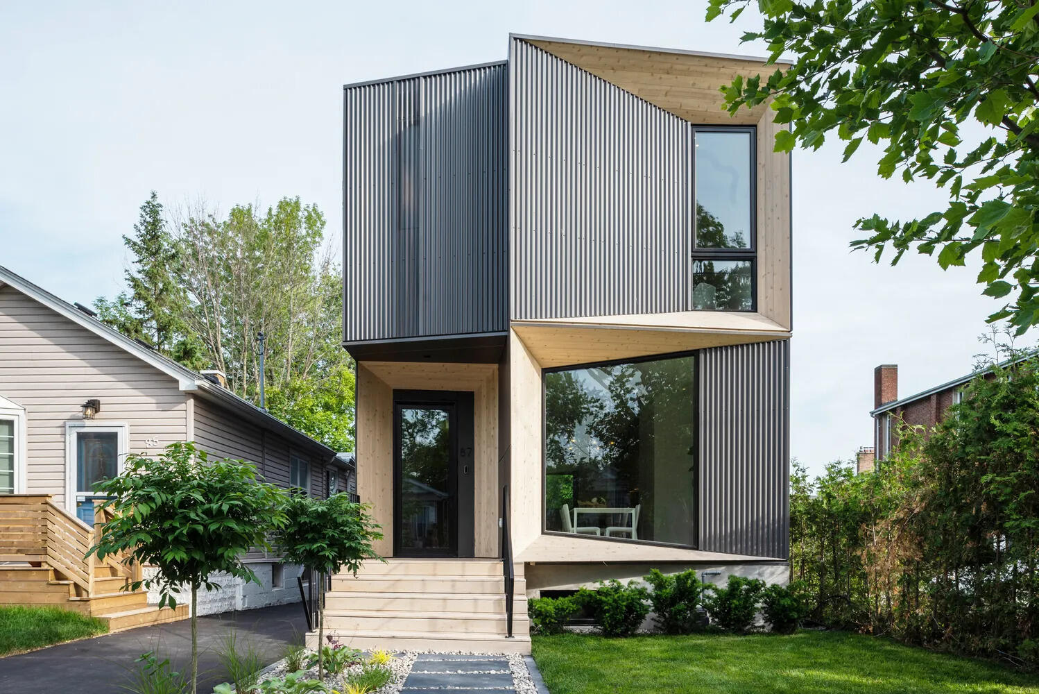 A striking modern home in Toronto defined by sharp angles, warm timber cladding, and dark steel siding. Tesseract House stands out through geometry and contrast.