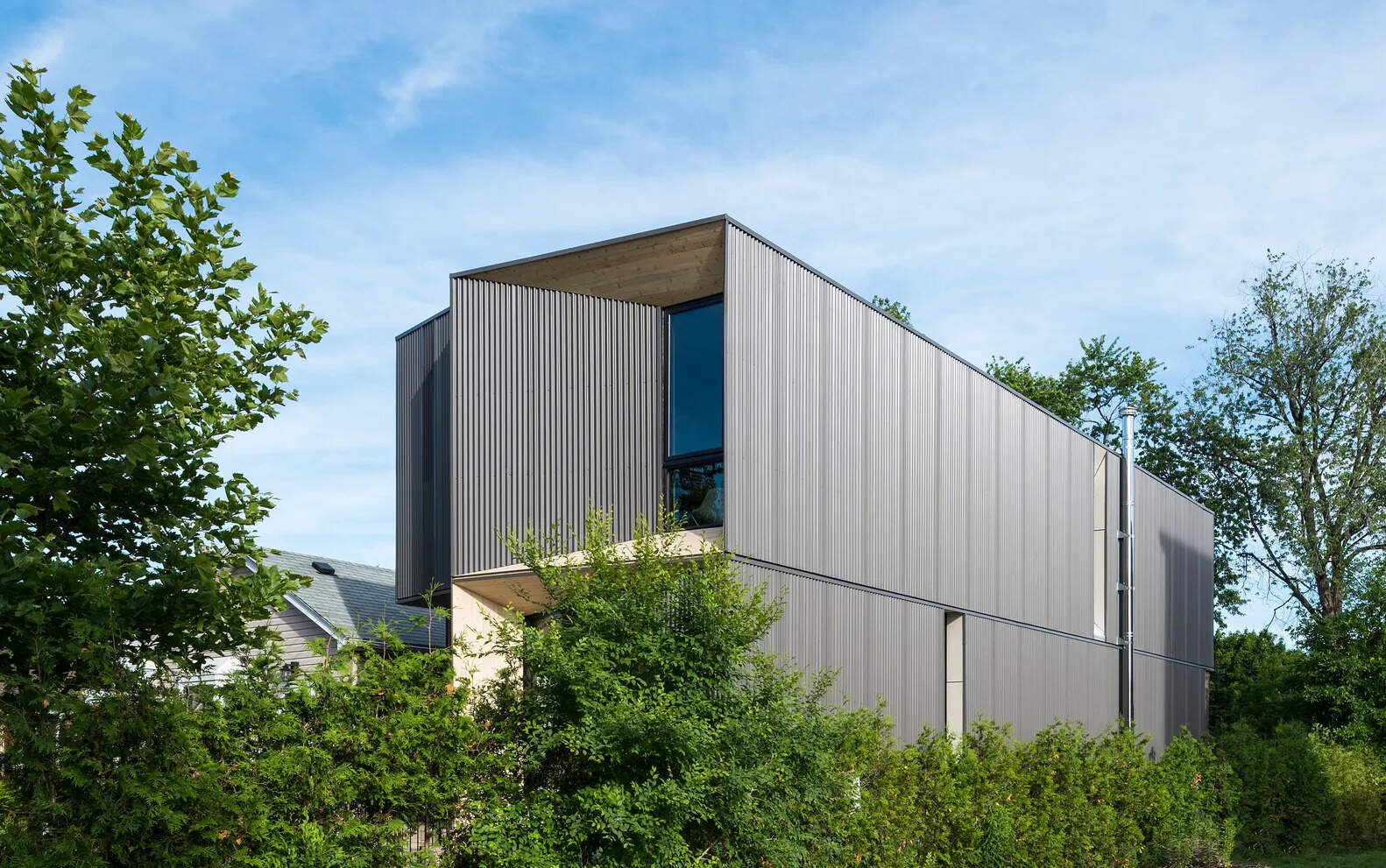 Angled timber elements contrast black window frames and corrugated steel, creating a bold yet refined exterior for this contemporary Toronto residence.