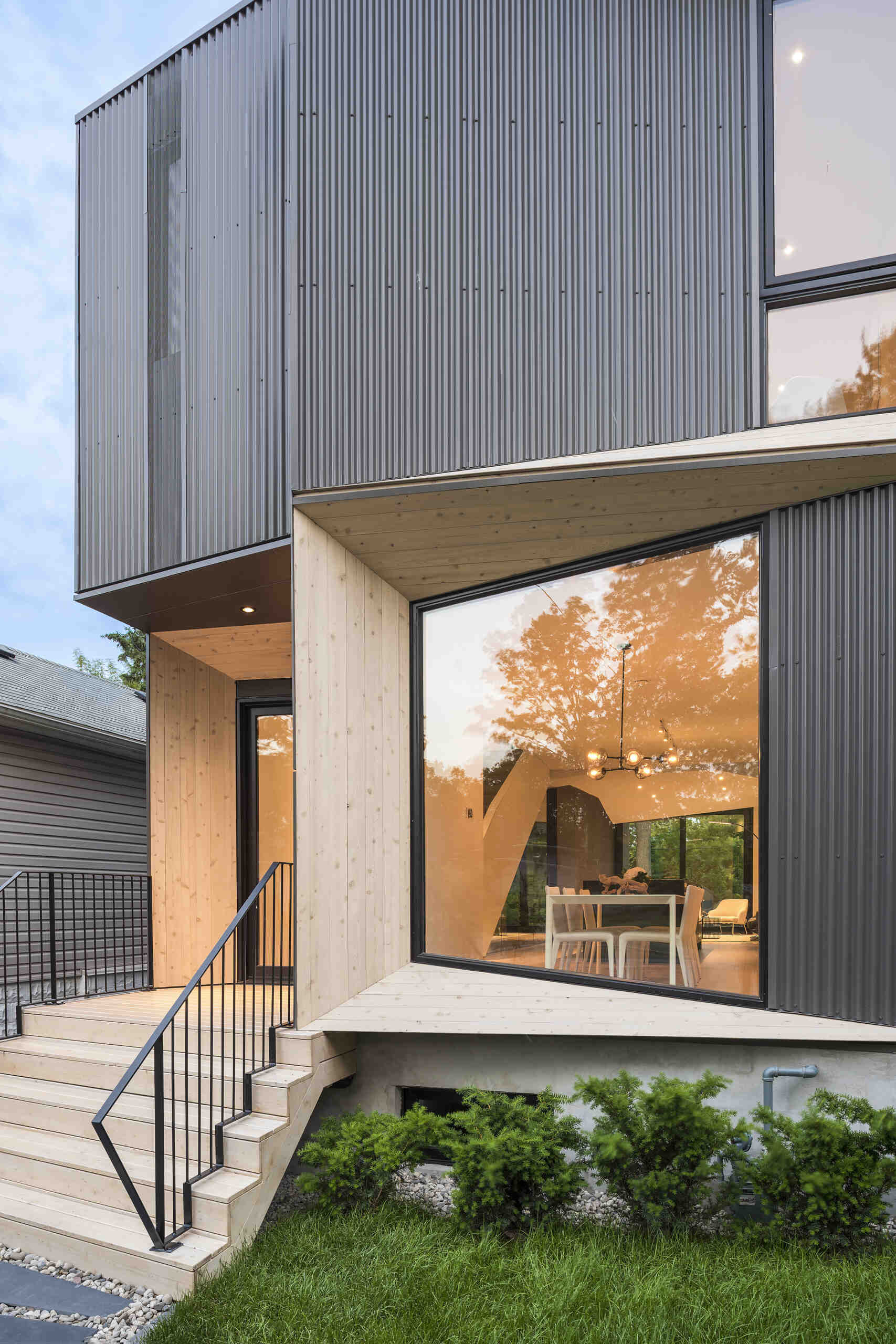 Angled timber elements contrast black window frames and corrugated steel, creating a bold yet refined exterior for this contemporary Toronto residence.
