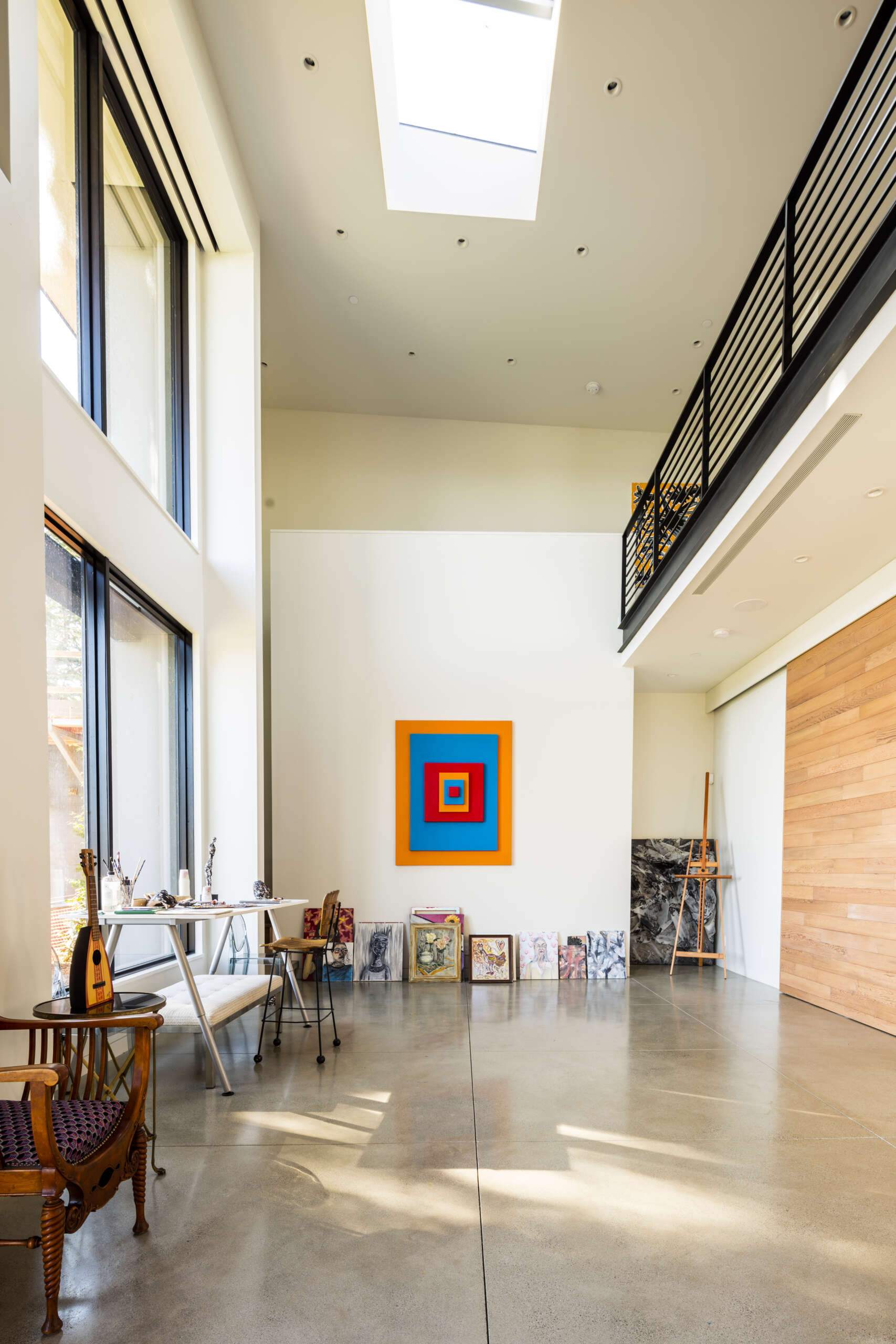 A double-height art studio with skylight and transom anchors one end of the house, filling the space with natural light.