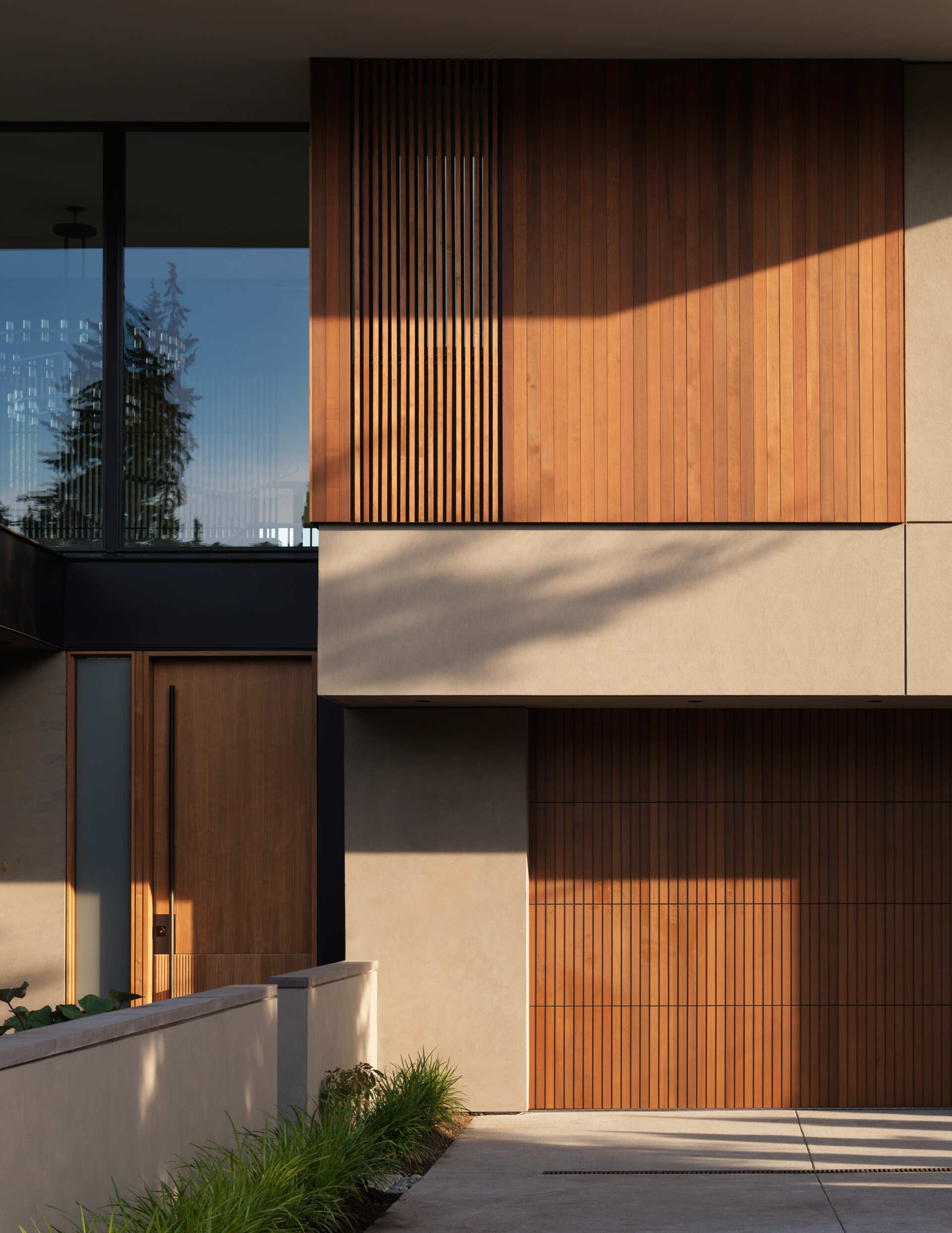 This modern home blends Pacific Northwest style with Thai-inspired wood screens. Sleek glass, steel, and warm walnut create a bright, inviting exterior.