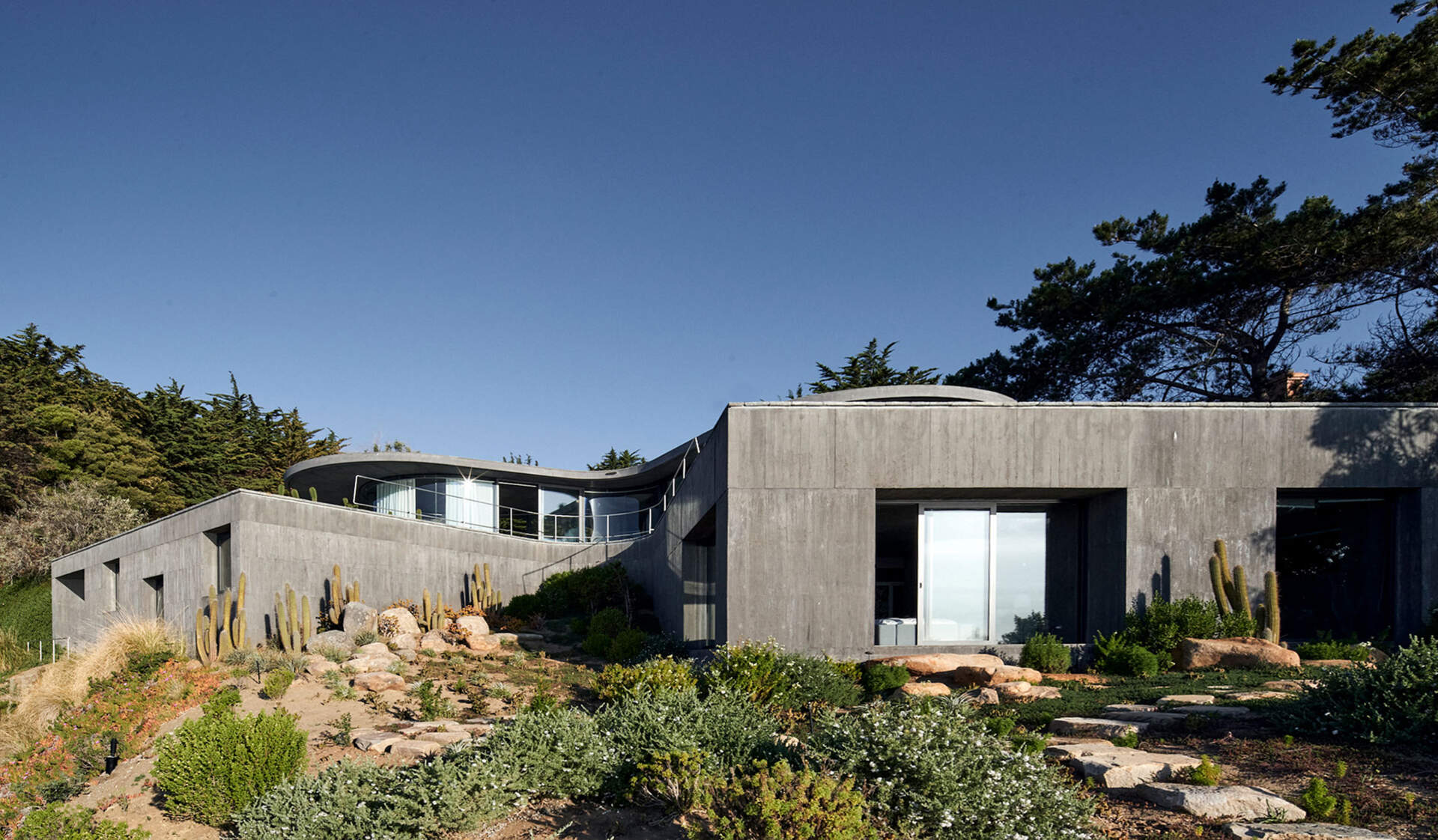 Private bedrooms and bathrooms embedded within the concrete podium, closely tied to the earth and terrain.