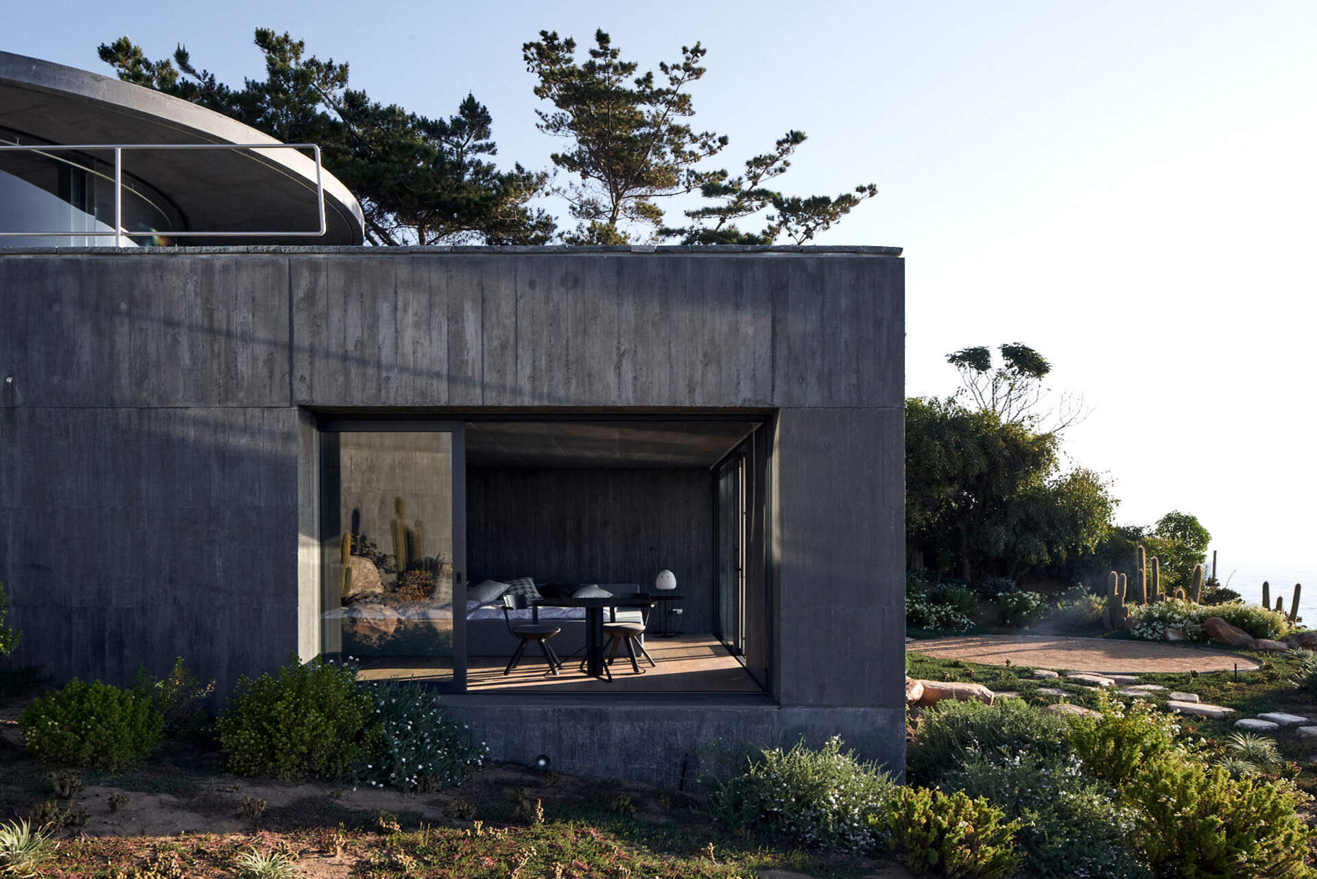 Private bedrooms and bathrooms embedded within the concrete podium, closely tied to the earth and terrain.
