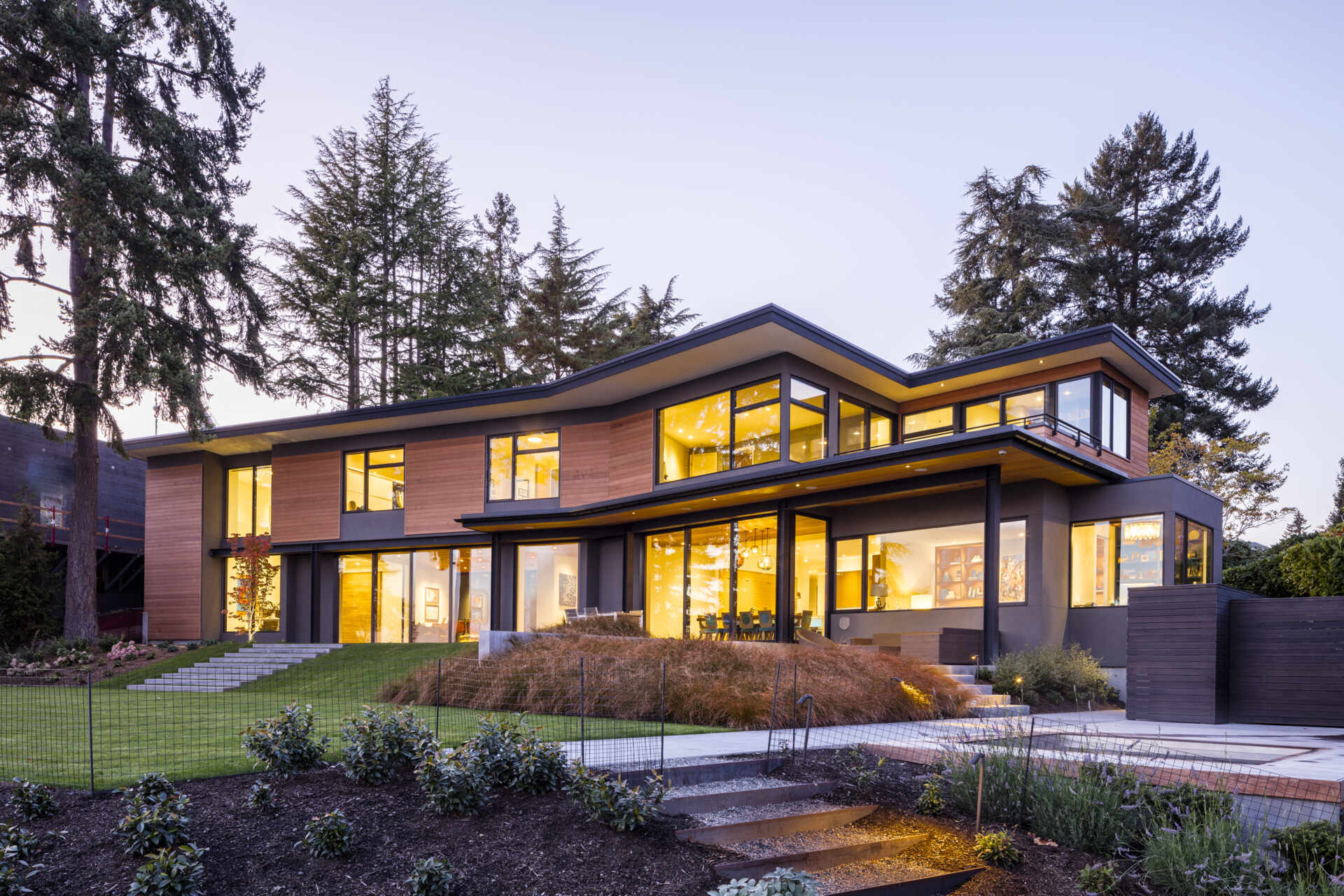 A boomerang-shaped lakefront home curves into the hillside, carefully orienting living spaces toward Mt. Rainier and Lake Washington.