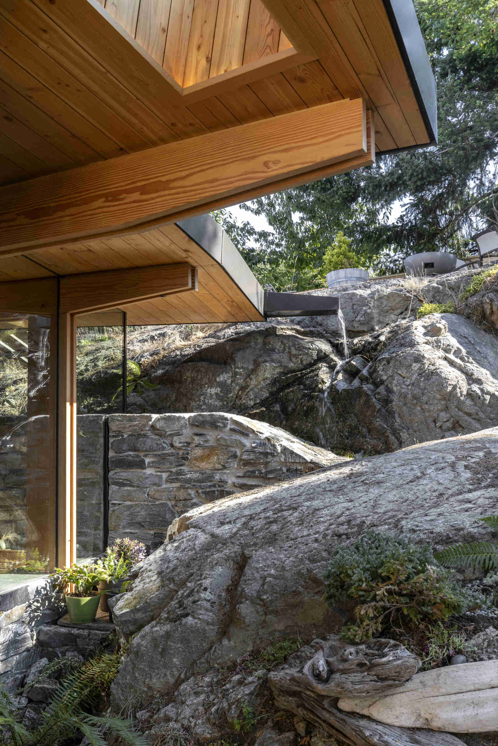 Rainwater is directed to splash onto the rock below, amplifying sound and later recycled to extend the experience through dry summer months.