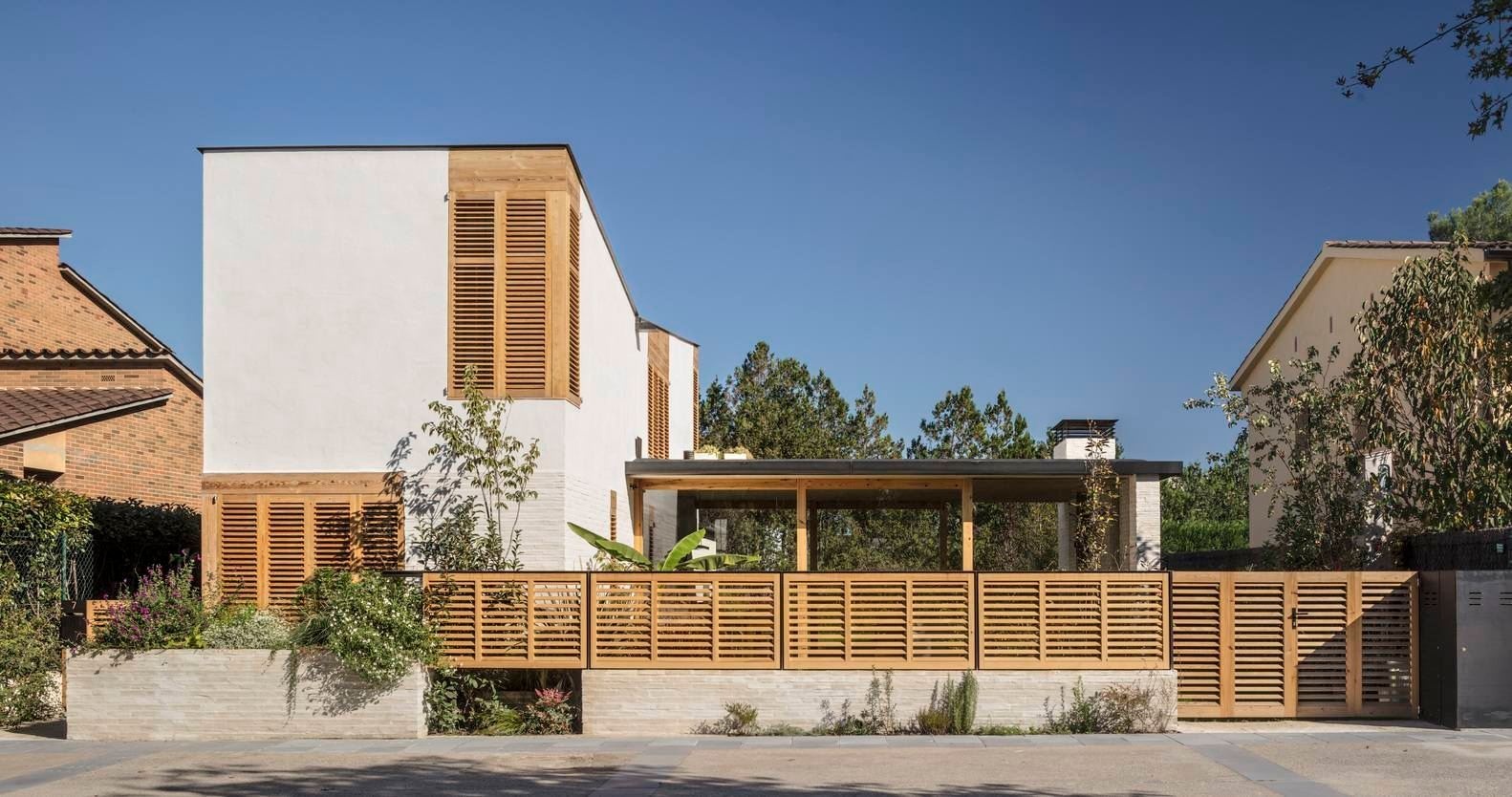 Esta casa familiar española se compone de dos volúmenes contrastantes, un esbelto volumen vertical que protege la privacidad y una zona de entretenimiento acristalada y completamente abierta al jardín.